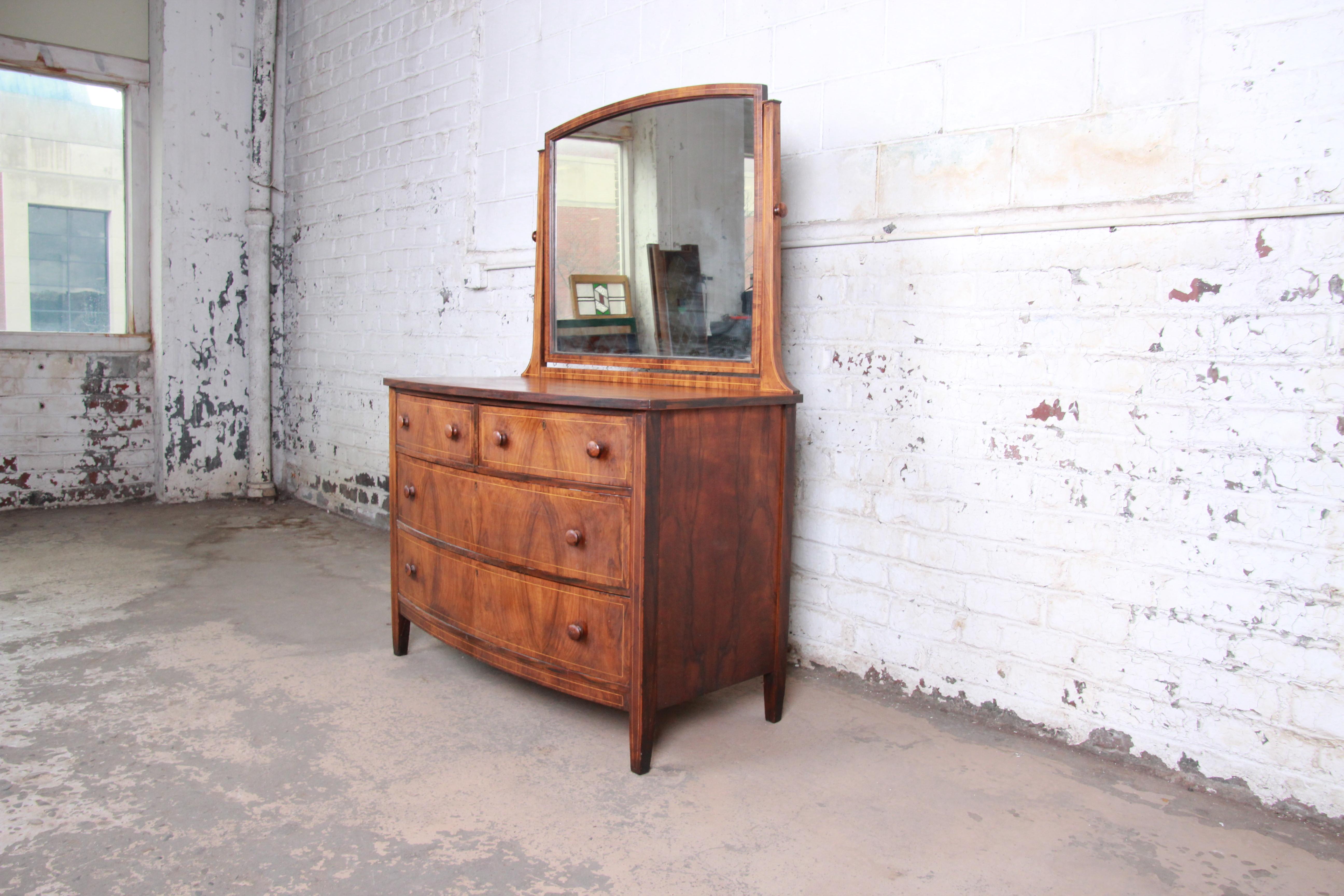 A gorgeous antique burled walnut dresser with mirror by Spencer & Barnes Co. of Benton Harbor, MI. The dresser features stunning book-matched wood grain with string inlay and a nice traditional Early American style. It offers good storage, with four