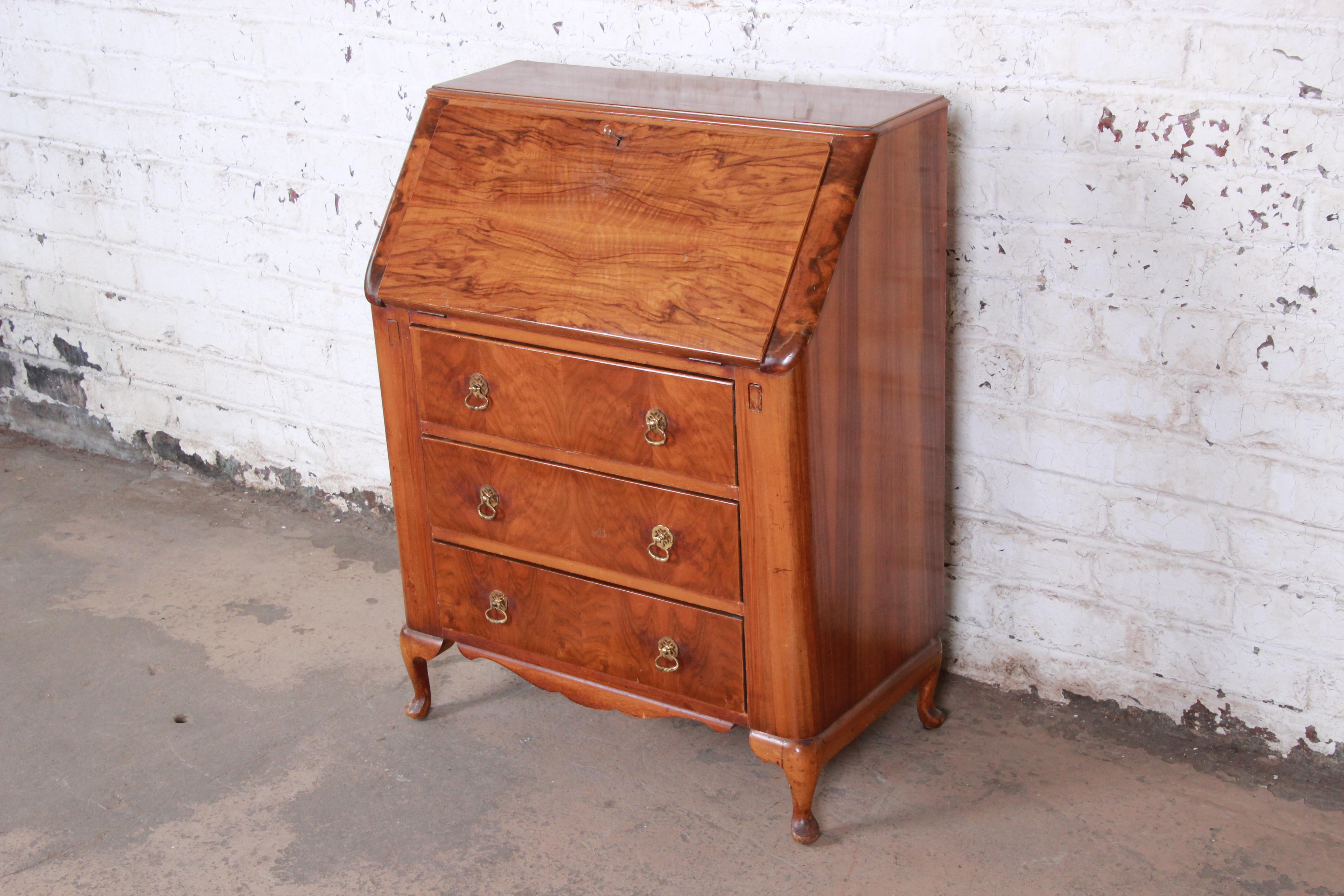 A gorgeous antique burled walnut drop-front secretary desk by Lebus Furniture, circa 1940s. The desk features stunning wood grain and Queen Anne style legs. It offers good storage, with a single drawer and several cubbies behind the drop front and