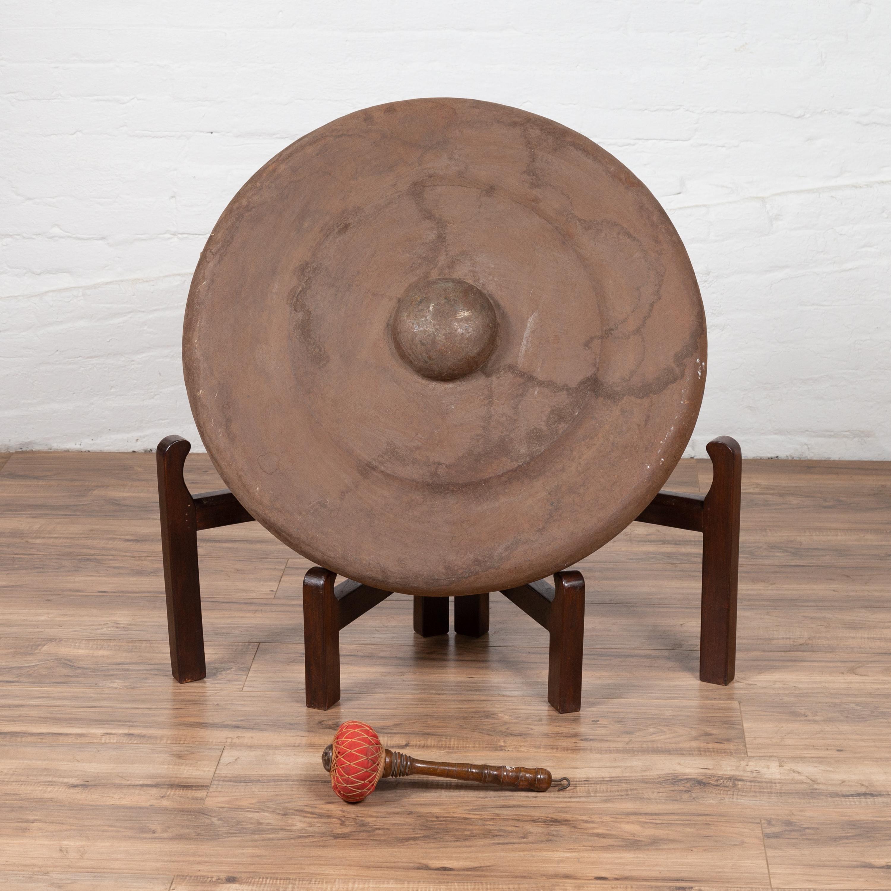 An antique Burmese bronze temple gong with mallet from the early 20th century. Please note that the base is not included. Born in Burma during the early years of the 20th century, this exquisite bronze temple gong features a traditional circular