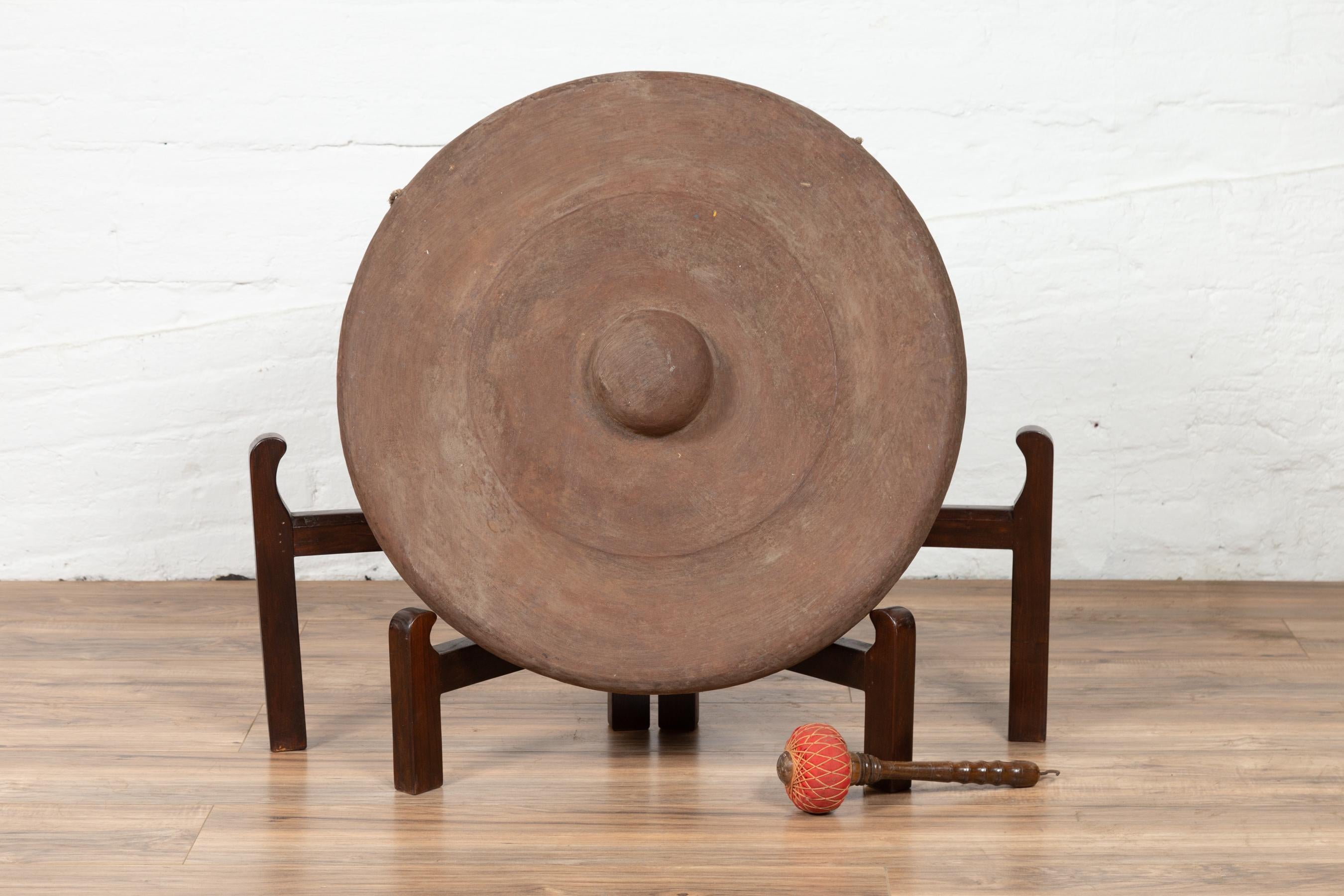 An antique Burmese bronze temple gong with mallet from the early 20th century. Please note that the stand is not included. Born in Burma during the early years of the 20th century, this exquisite bronze temple gong features a traditional circular