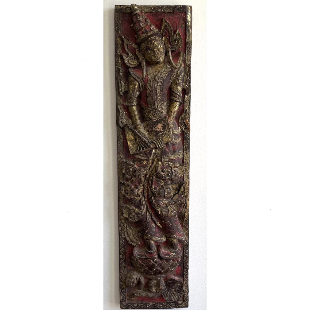 Antique Burmese Carved Wood Panel of a Court Scribe. The standing heavenly being holds a manuscript with a brush in the right hand writing scripture on an accordian style book while standing on a lotus pedestal. A high relief carving of teak with a