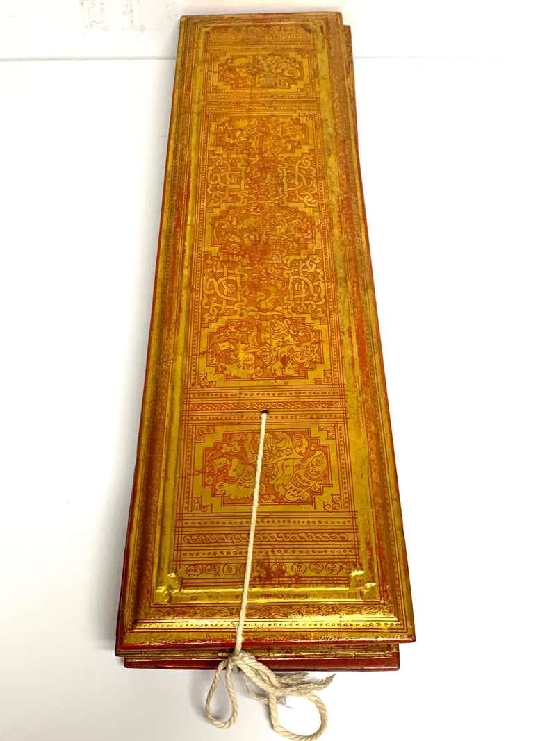 An exceptional 19th-century Burmese Kammavaca manuscript, composed of 14 lacquered palm-leaf-style panels, each meticulously decorated in orange and gold lacquer with intricate motifs and sacred text. Measuring 6 inches high by 24 inches wide and