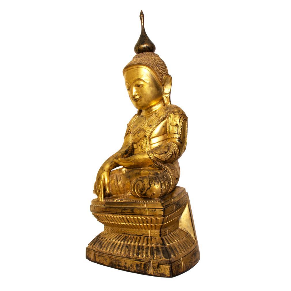 Antique Burmese Shan Wood, Lacquer and Gold Leafed Buddha, 19th Century. The image sits on a waisted lotus base with raised lacquer  details, seated in padmasana, the lotus position with the hands having four fingers all of the same length in the