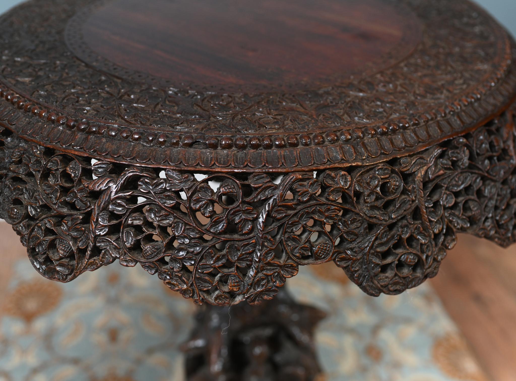 You are viewing an intricately carved antique Burmese side table
Circa 1880
The round top features an intricately pierced and relief-carved border, showcasing dense foliate and floral motifs typical of colonial Indian craftsmanship made for the