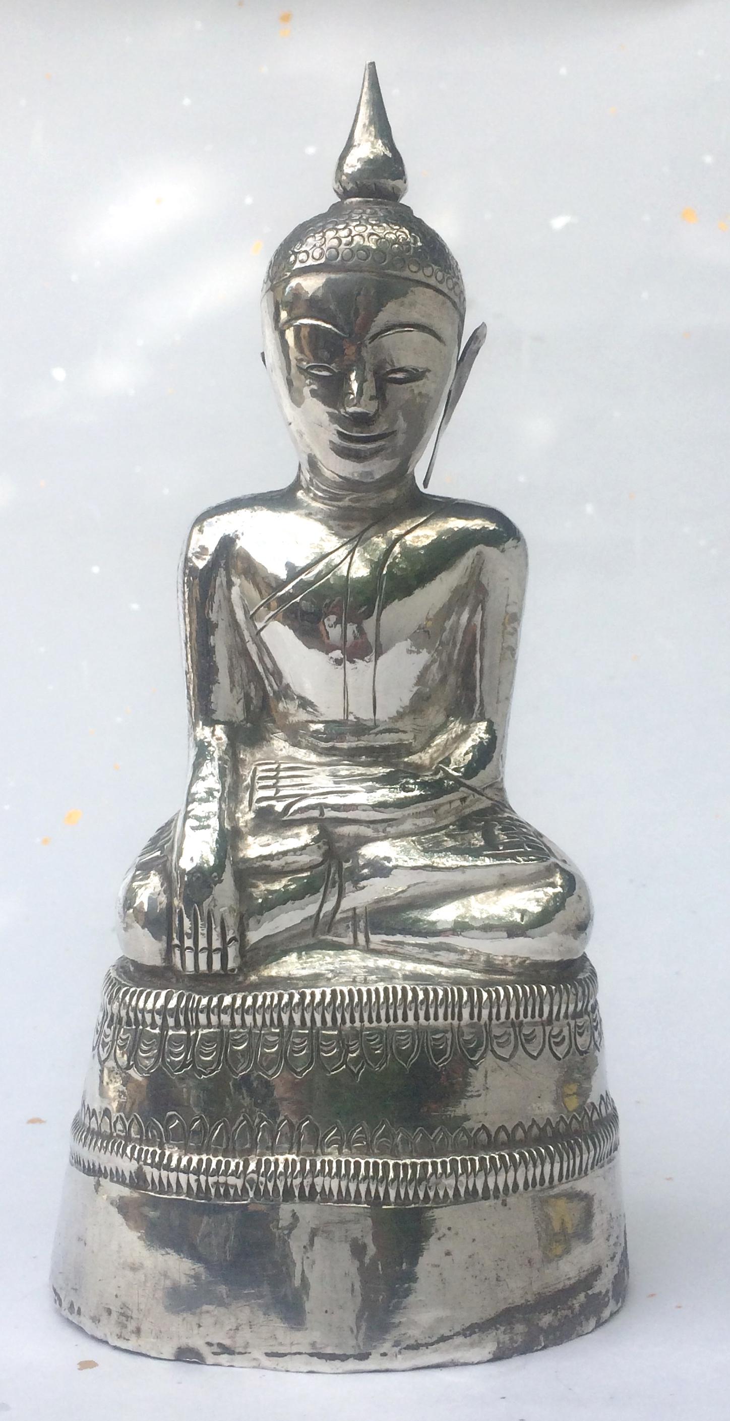 Burmese Silver Buddha, crafted of sheet silver over a composite clay core, depicted in padmasana with the hands in the bhumisparsa mudra seated on top of a two tiered base with edge incised decoration, the etched decoration on the image includes