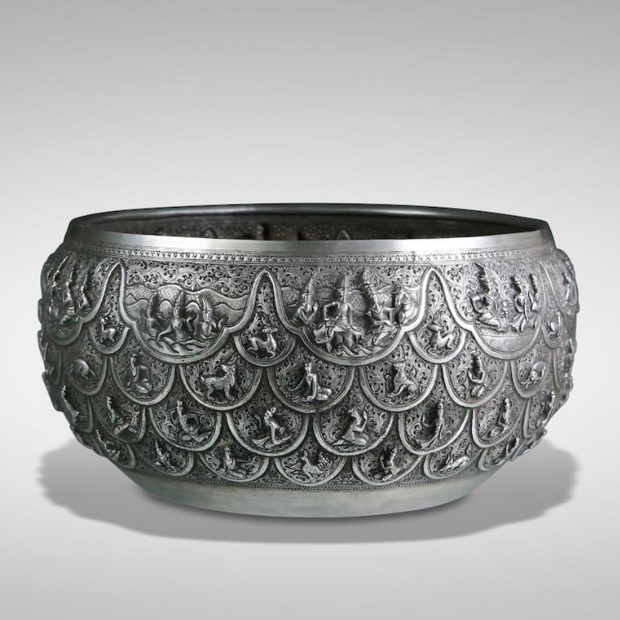 A SILVER OFFERING BOWL WITH SCENES FROM THE VIDHURA-PANDITA JATAKA, LOWER BURMA (MYANMAR), DATED 1901. 
A hammered repoussé Buddhist beggar’s bowl form with high relief  design depicting scenes from the Vidhura-Pandita Jataka on the upper row of
