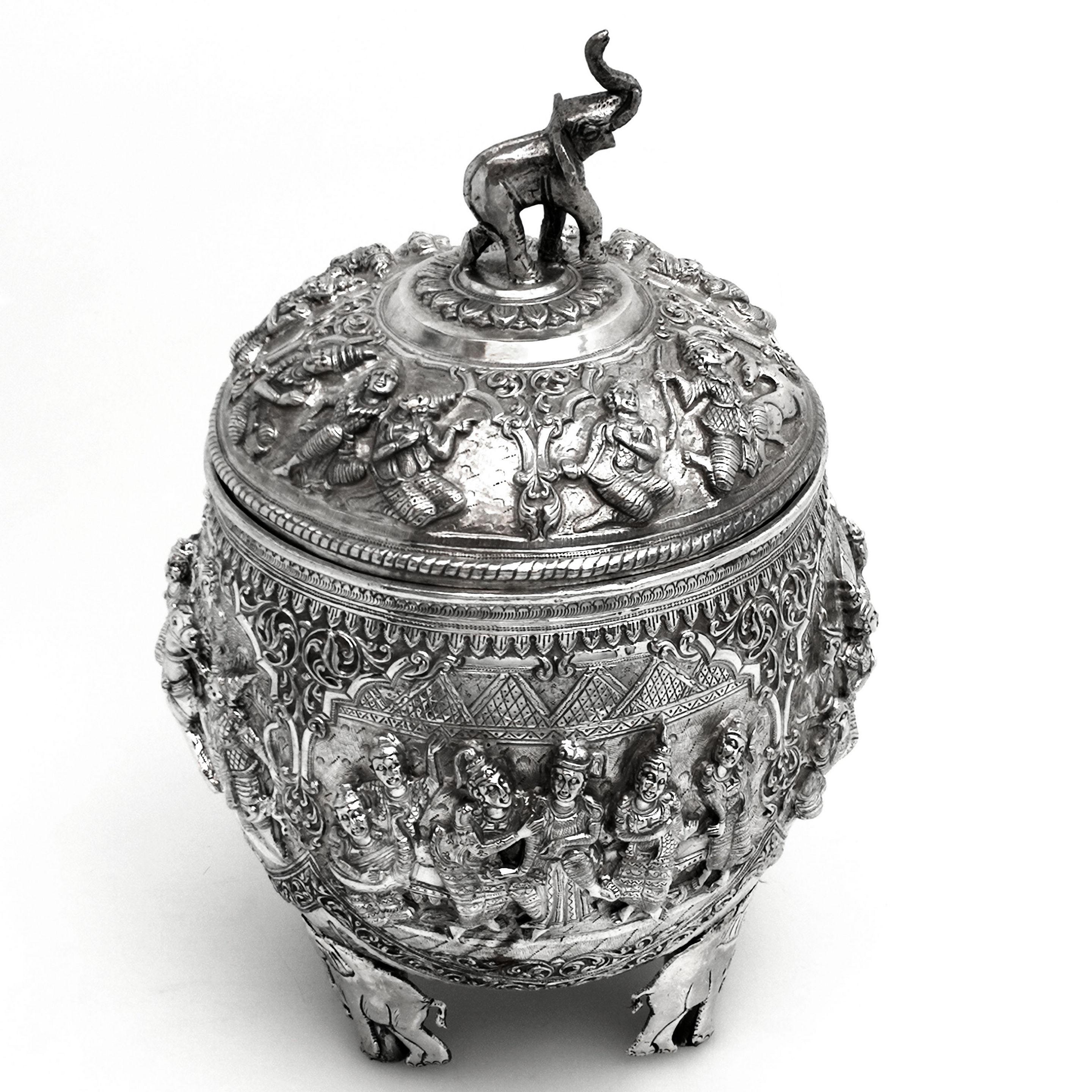 A magnificent Antique Burmese silver covered Bowl with a tightly fitted push lid. The entire exterior of the Box is covered with ornate chased scenes in deep relief. These Images are created in the traditional antique Burmese style and show images