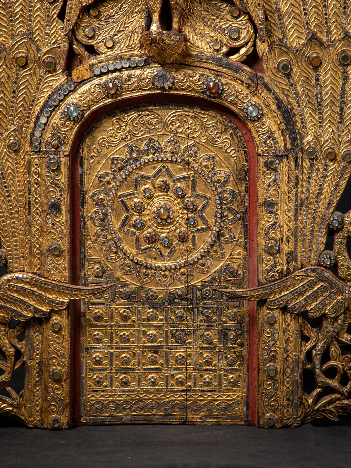 Diese antike birmanische Holztafel ist ein beeindruckendes Kunstwerk im Mandalay-Stil aus dem 19. Jahrhundert, das aus massivem Holz gefertigt und reich mit 24-karätigem Gold vergoldet ist. Mit einer Höhe von 110,5 cm, einer Breite von 79 cm und