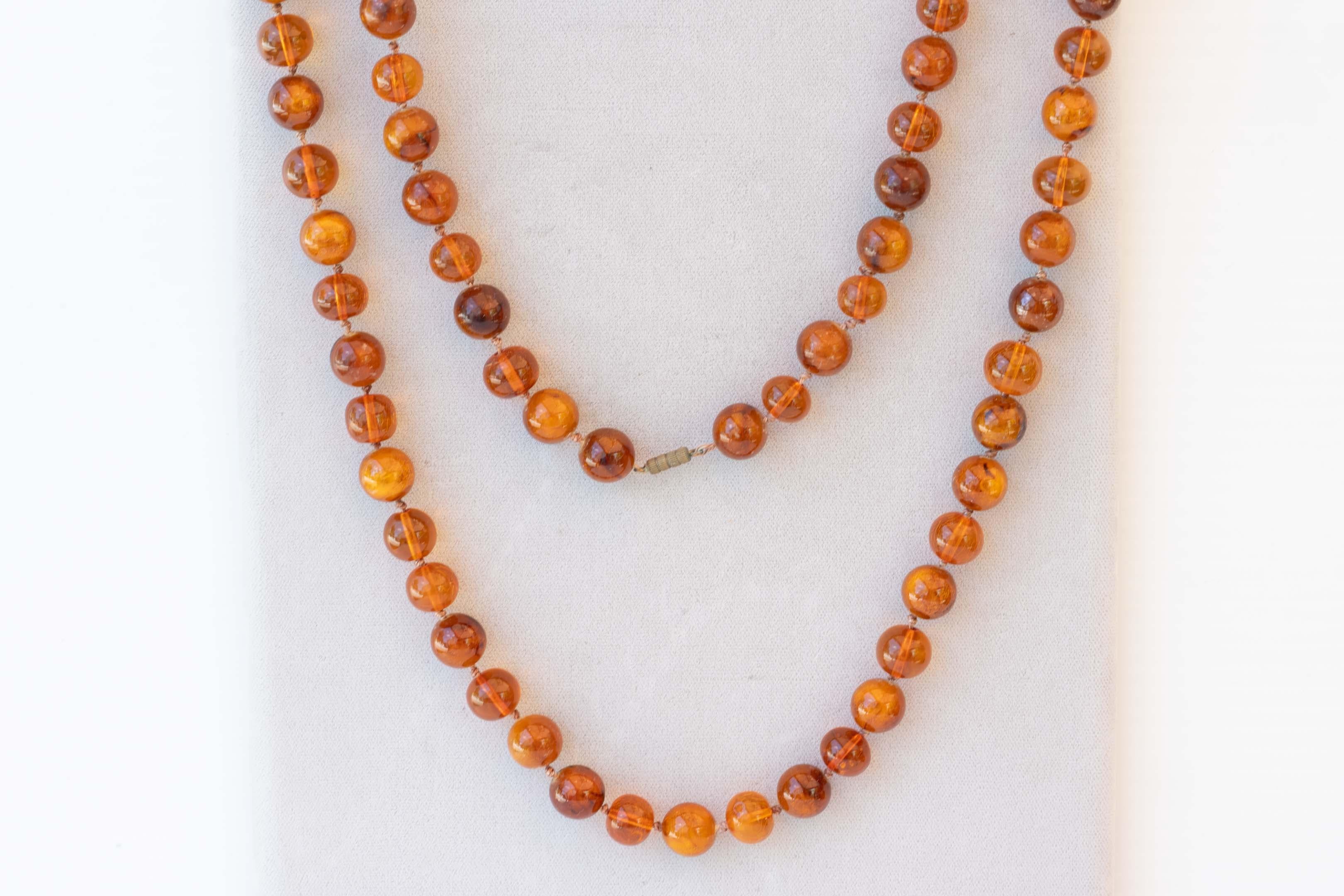 Genuine antique Burmite amber 36-inch necklace with round beads measuring 13 1/2 mm - 14 imm in diameter, 61 beads with knots in between. Provenance from the Burma region, in good condition. Weighs 81 grams, tested in salt water. 