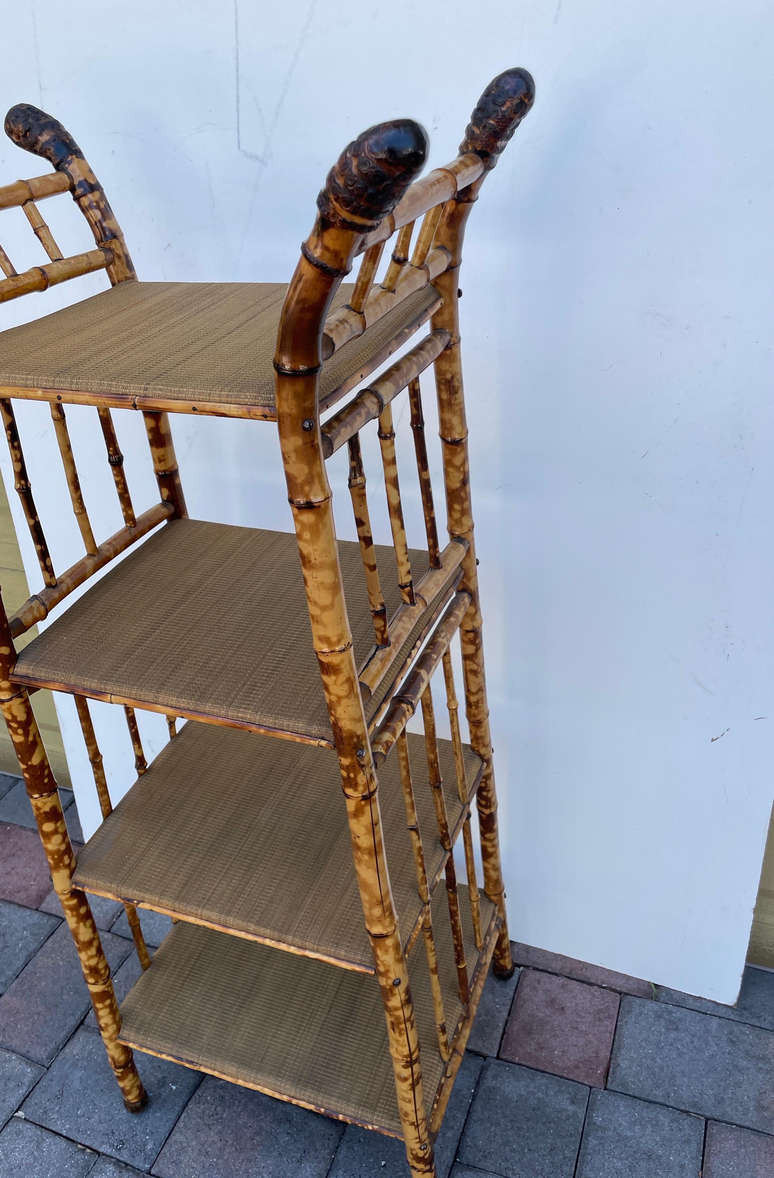 Etagere in bambù bruciato antico con quattro ripiani. Ogni ripiano è avvolto in un tessuto di rafia. Ognuna delle quattro gambe ha la sua radice naturale in cima. Un pezzo molto raro e meraviglioso.