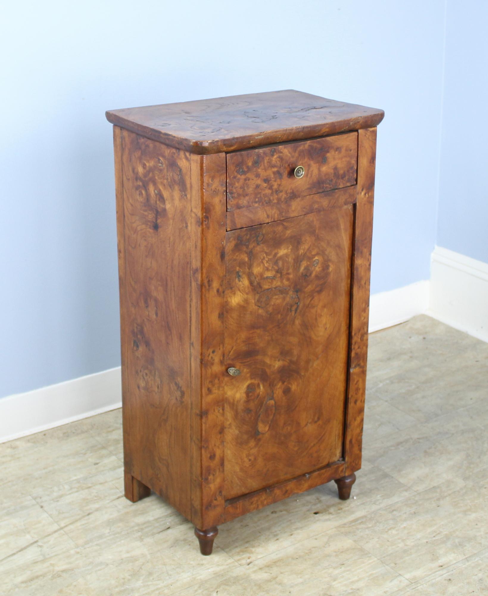 Terrific graining on this burr elm side cabinet, with a nice thick top with interesting knot holes and old repair. Sweet little drawer, and a small bronze knob. Lovely turned tear drop feet. Great storage for a practical and handsome nightstand.