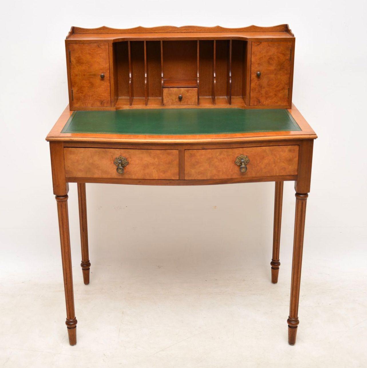 This antique burr walnut writing table desk is in good condition and has some useful features. The top section has two cupboards, a small central drawer and shaped compartments. The tooled leather writing surface is original. There are two drawers