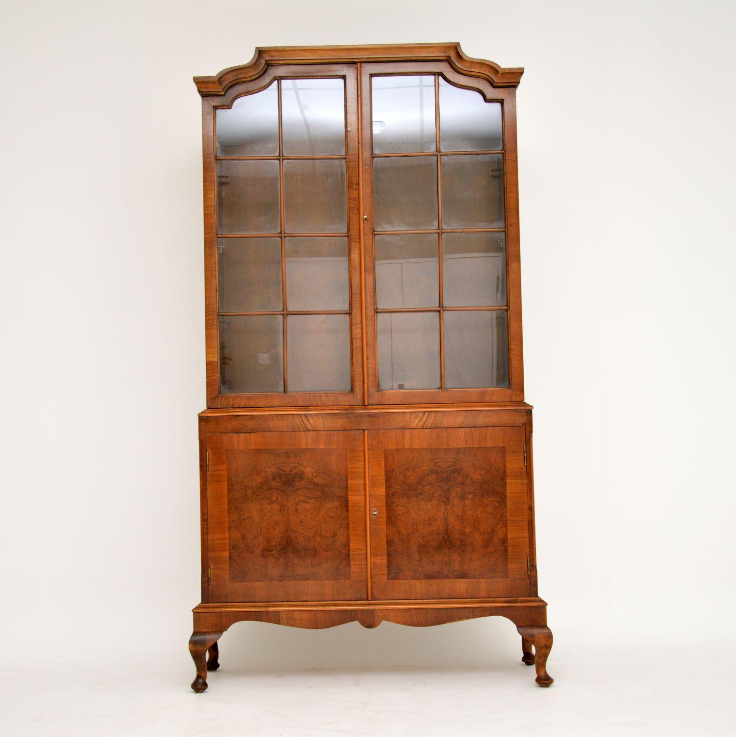 Antique two section astral-glazed walnut bookcase with a burr walnut panelled cupboard below and sitting on Queen Anne feet. It has a shaped top and the bottom section has chamfered edges. There are adjustable shelves in the top section and a loose