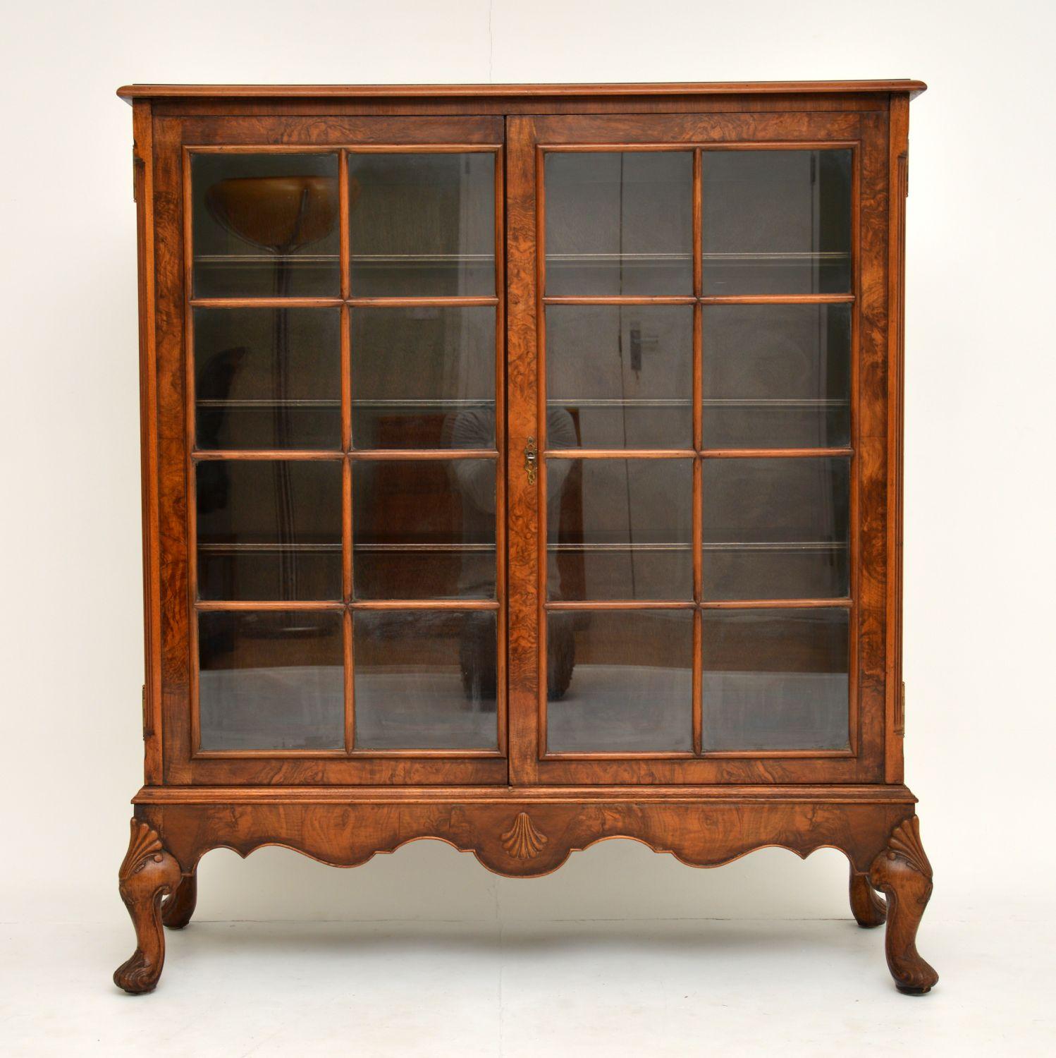 A stunning antique bookcase in burr walnut, this dates from the 1920s period. It is of very fine quality, with many beautiful details.

The legs have deep heavy carving and the base has a beautiful shape. The walnut veneers and colour are