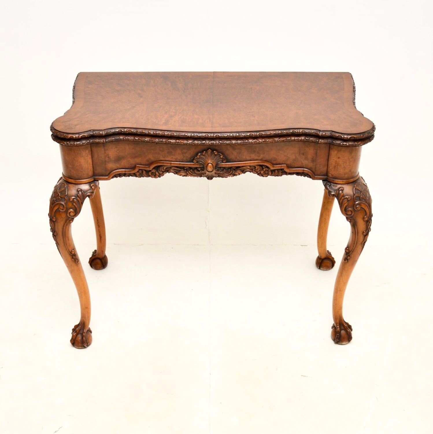 A fantastic antique burr walnut card table of the highest order. This was made in England, it dates from around the 1900-1920 period.

It is of outstanding quality, with fine and intricate carving throughout. The burr walnut grain patterns and