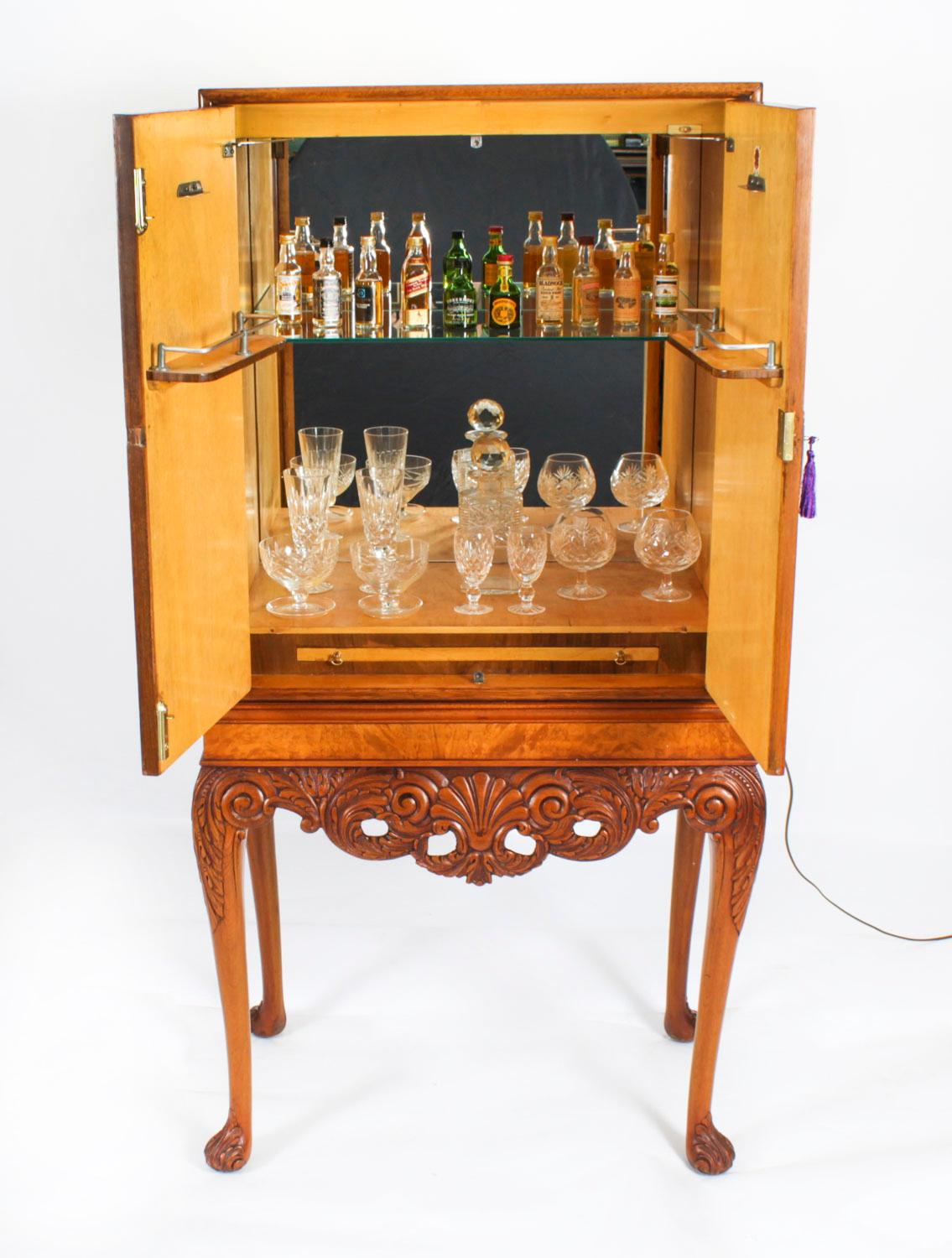 Si tratta di un fantastico mobile da cocktail antico in radica di noce con splendide decorazioni intagliate a mano e un set di bicchieri, realizzato da Gold Feather Products di Leeds, risalente alla metà del XX secolo.

Le ante dell'armadio si