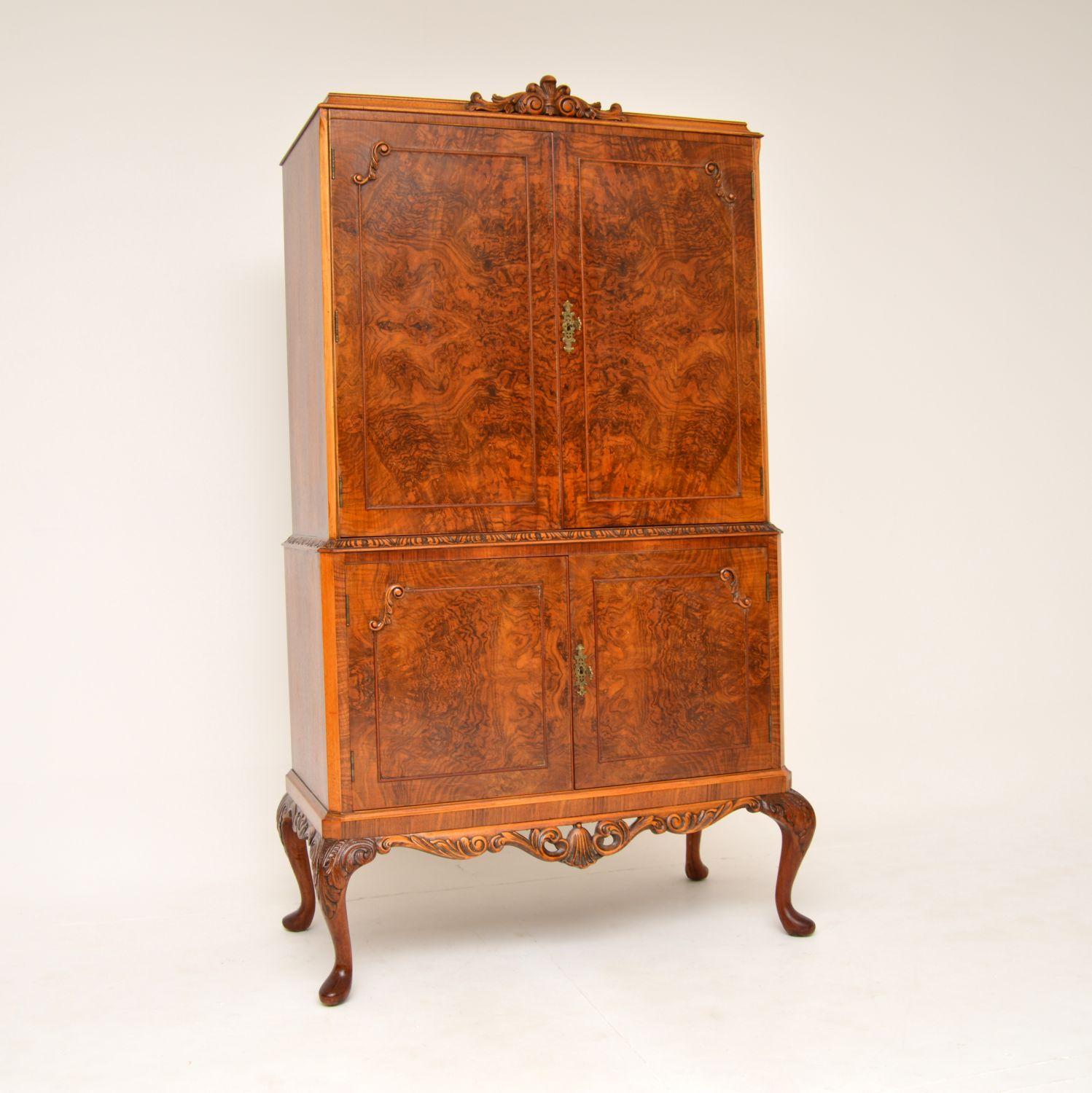 A beautiful antique burr walnut cocktail drinks cabinet in the Queen Anne style. This was made in England, it dates from around the 1930’s. It is of superb quality, with absolutely gorgeous grain patterns and wonderful carving. The upper cabinet is