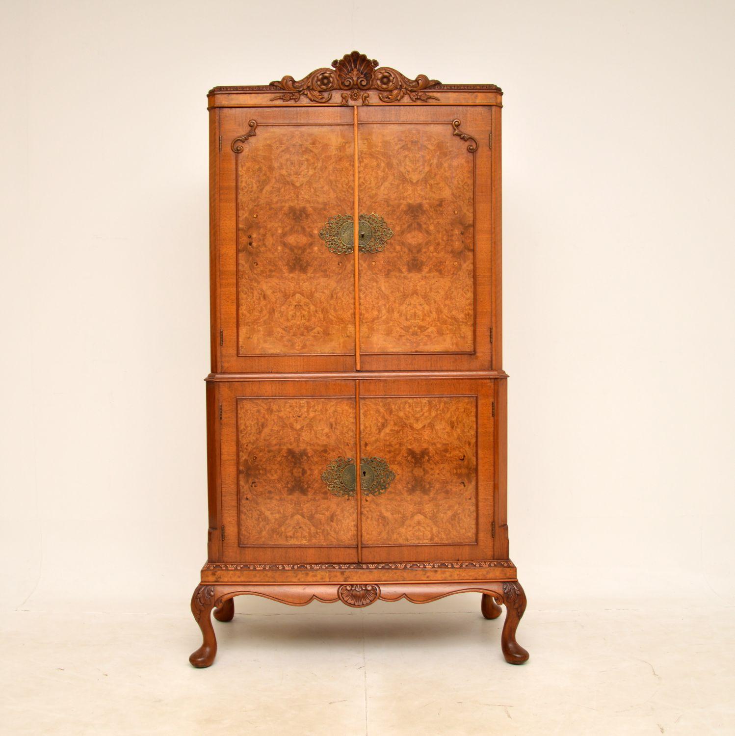 A stunning antique walnut drinks cabinet in the Queen Anne style. This was made in England, it dates from around the 1920-1930s.

It is of superb quality, with spectacular walnut grain patterns and fine, crisp carving throughout. The top section