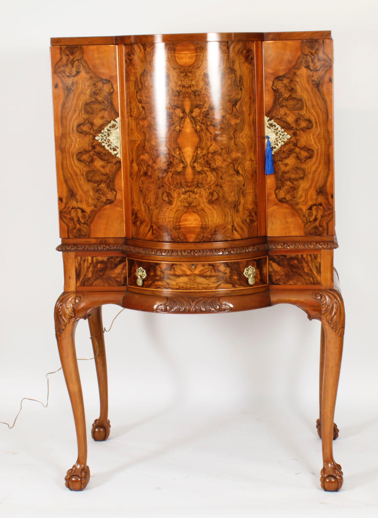 This is a fantastic antique Queen Anne Revival  burr walnut cocktail cabinet with fitted and mirrored revolving interior, dating from C 1920.

The two doors opens to a fitted mirrored interior with a central drum revolving section with pop out