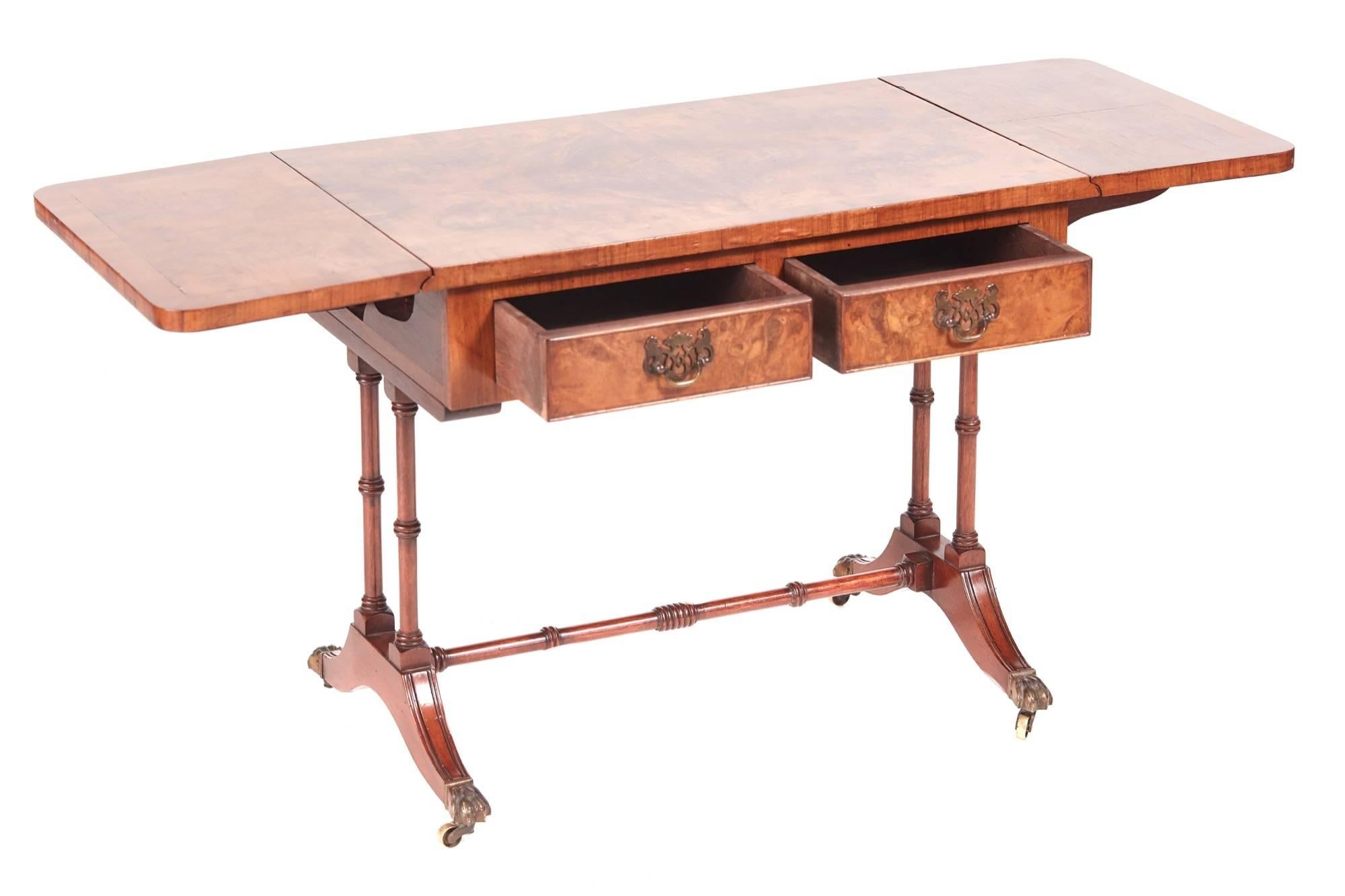 Antique burr walnut coffee table, having a lovely burr walnut crossbanded top with two drop leaves, two drawers to the frieze with original brass handles, supported by four turned columns, standing on shaped sabre legs with original brass castors