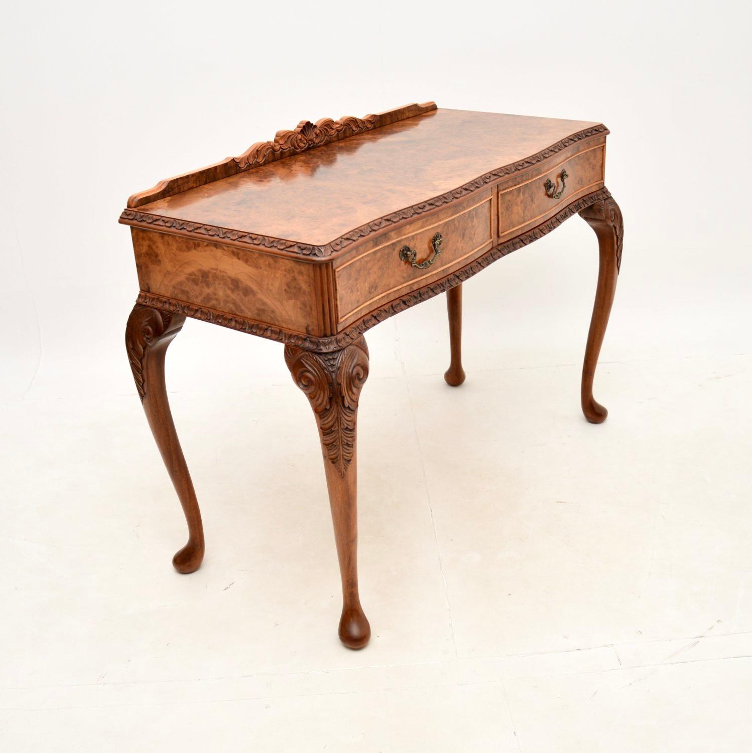 A beautifully made antique burr walnut console / side table. This was made in England, it dates from around the 1930’s.

The quality is fantastic, this has intricate carving all round the edges and gorgeous burr walnut grain patterns. It sits on