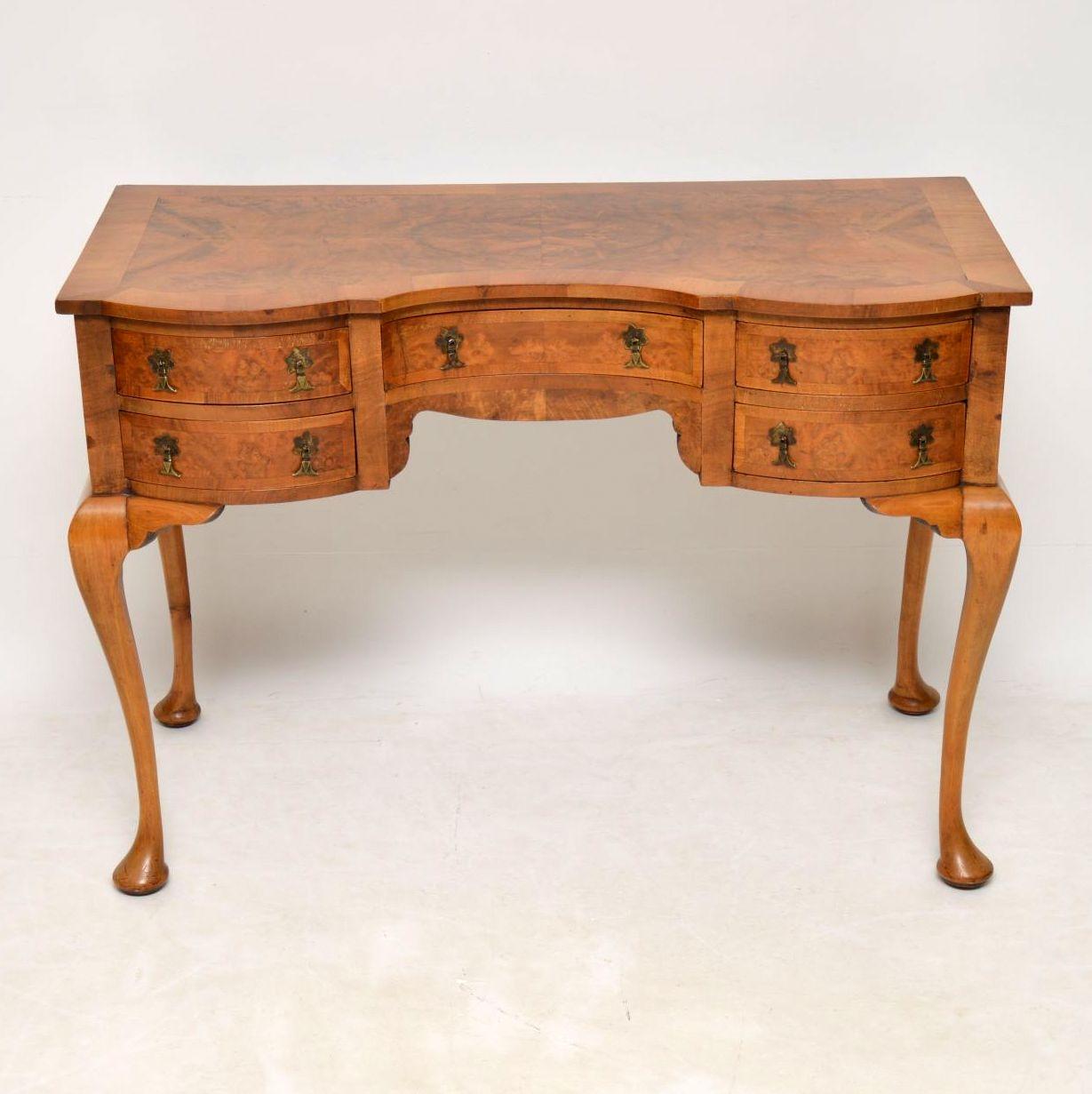 This well shaped antique walnut table could be used as a desk, dressing table, or just a side table. It’s fine quality and dates to around the 1920s period. The top is burr walnut with cross banding and the same goes for the drawers which have the