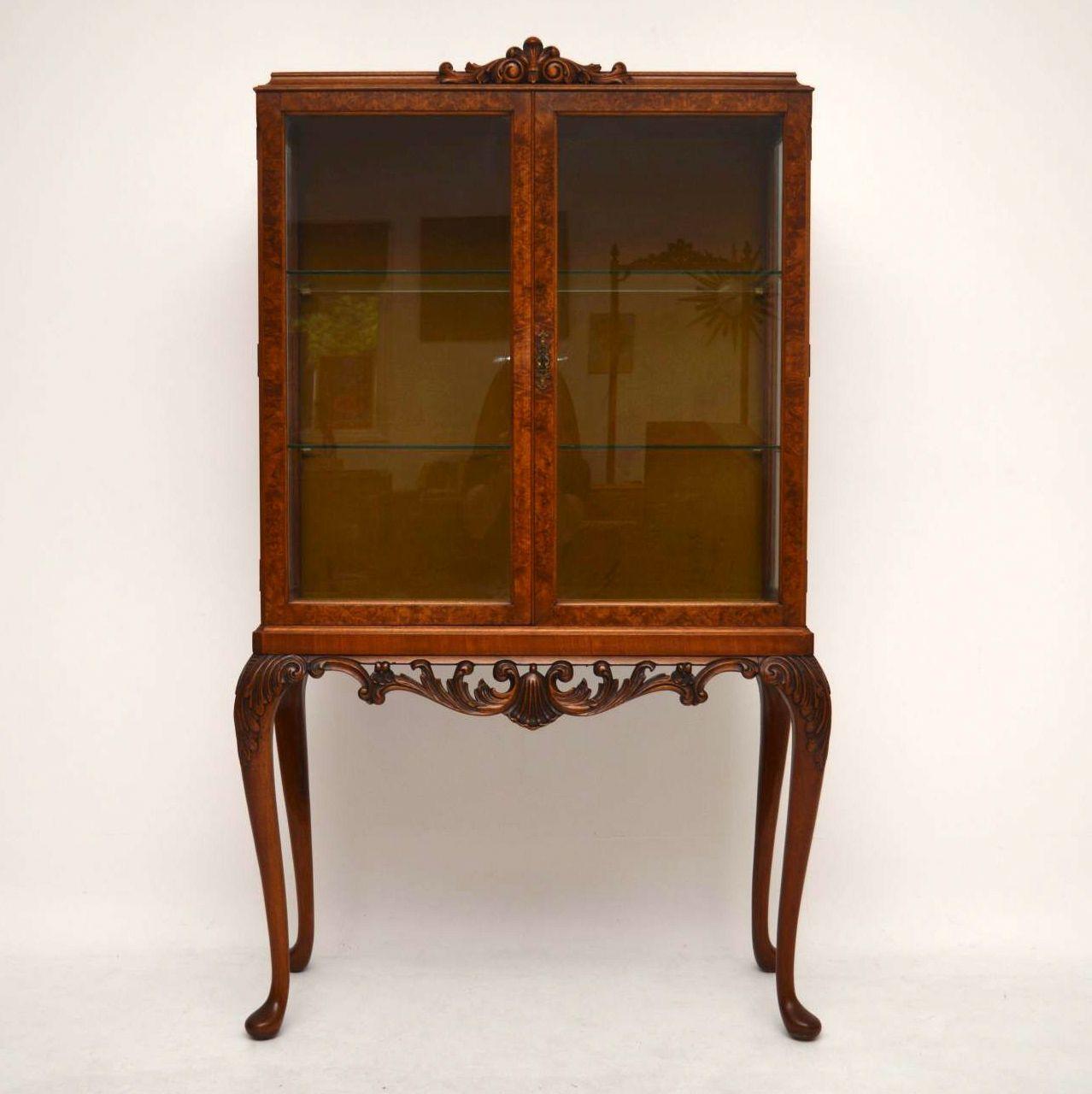 Fine quality antique walnut display cabinet in excellent condition, dating to circa 1920s period. The top section has two burr walnut glazed doors with two glass shelves inside and fabric on the back. It sits on well carved solid walnut legs with