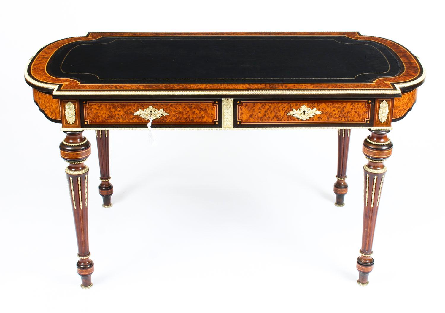 An elegant antique English Victorian burr walnut and ebonized writing table, circa 1870 in date.

The shaped burr walnut and line inlaid top features a striking ormolu border with a gold tooled inset black leather writing surface above twin fitted