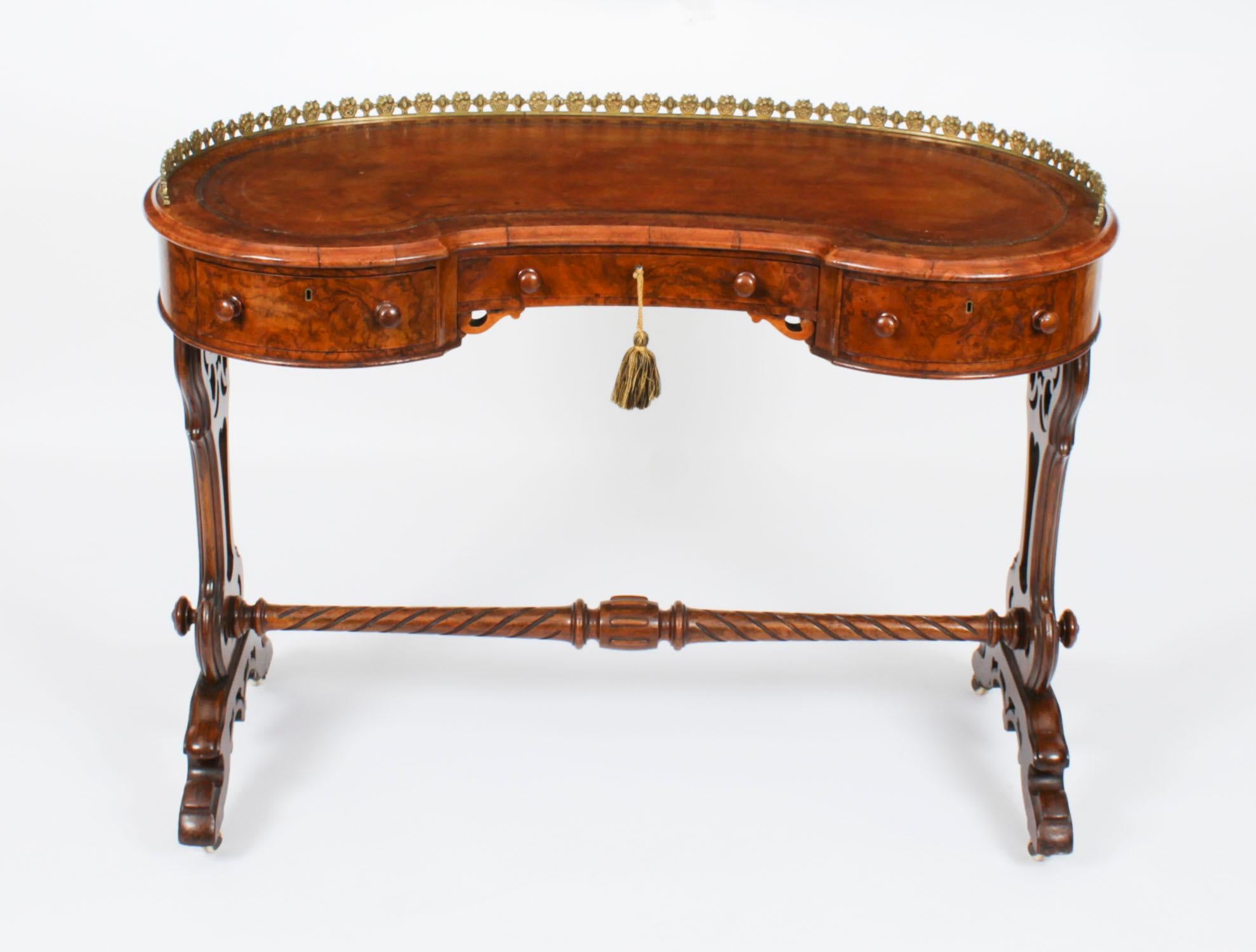This is a fabulous quality antique Victorian burr walnut kidney shaped writing table, circa 1860 in date.

The shaped top features a three quarter brass gallery with an inset gold tooled brown leather writing surface. the frieze has three useful