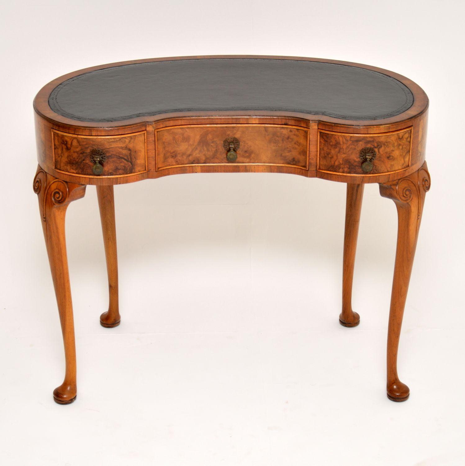 Antique kidney shaped burr walnut writing table with a tooled leather top and in excellent condition. This desk is Queen Anne style and of highest quality and dating to the 1920s period. It has three drawers with burr walnut fronts, fine dovetails