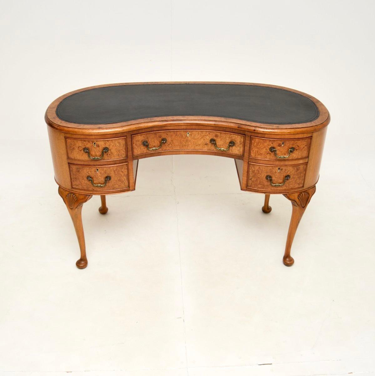 Magnifique bureau ancien en ronce de noyer avec dessus en cuir. Fabriqué en Angleterre, il date des années 1920 environ.

La qualité est exceptionnelle, le design est magnifique et la taille très pratique. Le plateau en forme de rein est doté d'une