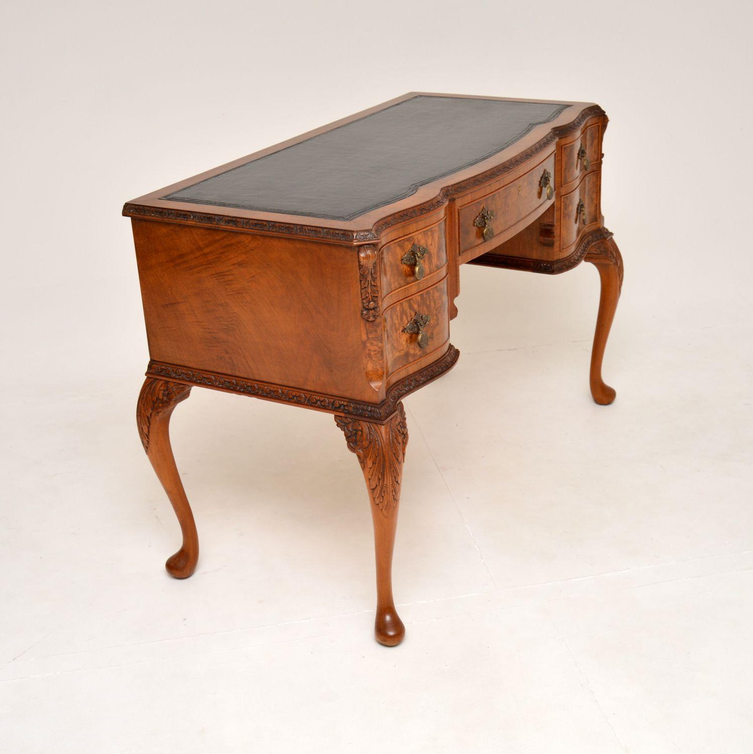 A stunning antique burr walnut leather top writing desk in the Queen Anne style. This was made in England, it dates from the 1920’s.

It is of superb quality, with beautiful and intricate carving all over the edges and base. This sits on cabriole