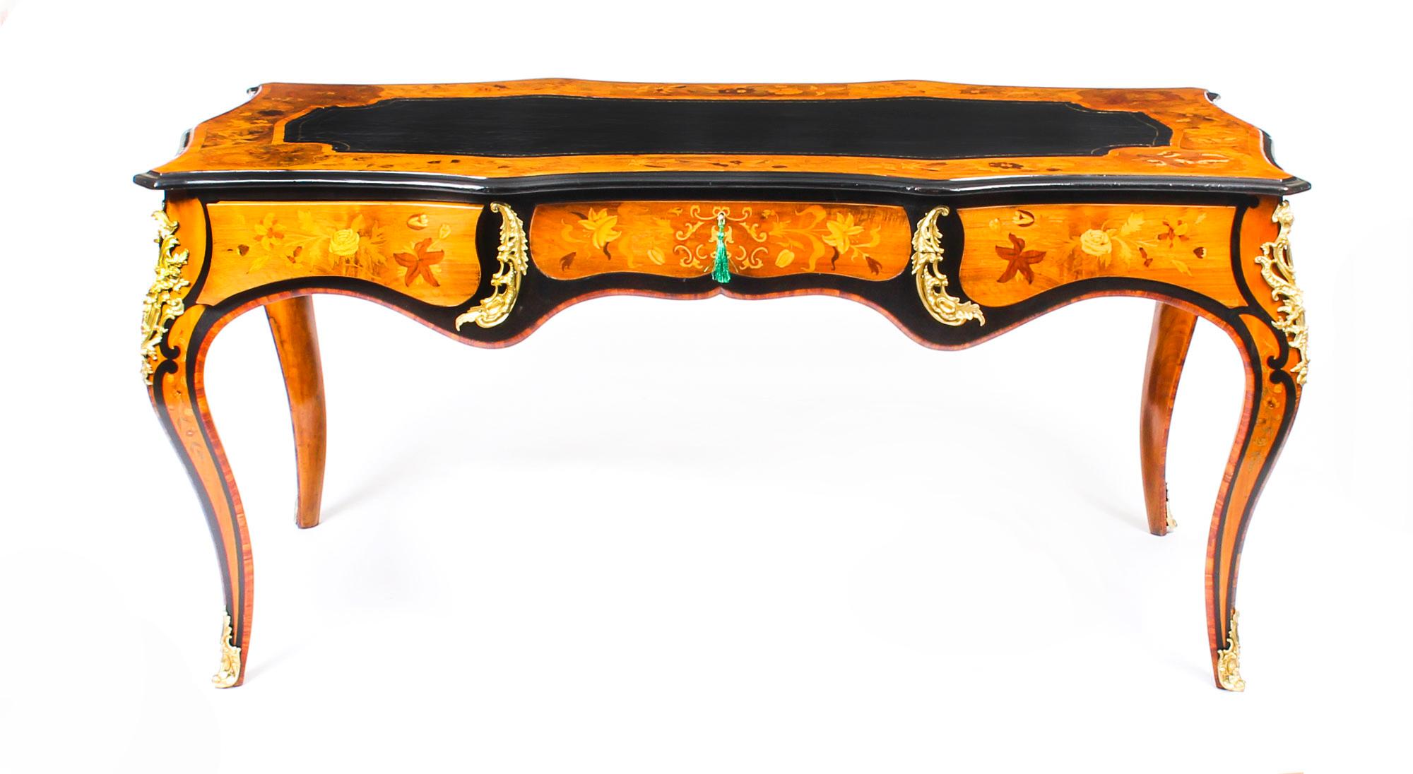 This is an absolutely stunning Louis revival burr walnut, ebonized, specimen marquetry, and ormolu-mounted bureau plat circa 1860 in date.
 
This fantastic bureau plat features a shaped top with an inset gilt tooled black leather writing surface,