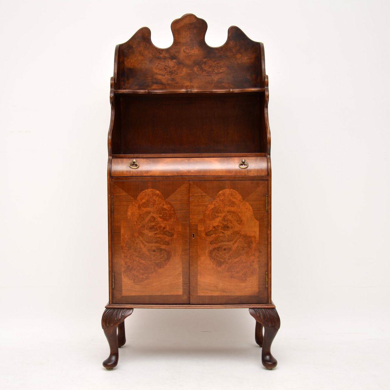Antique burr walnut cabinet with bookshelves above the cupboards.

This is a very useful piece of furniture, which could fit in many locations in the home.

The top & the sides are beautifully shaped out & it sits on carved feet. It has a curved