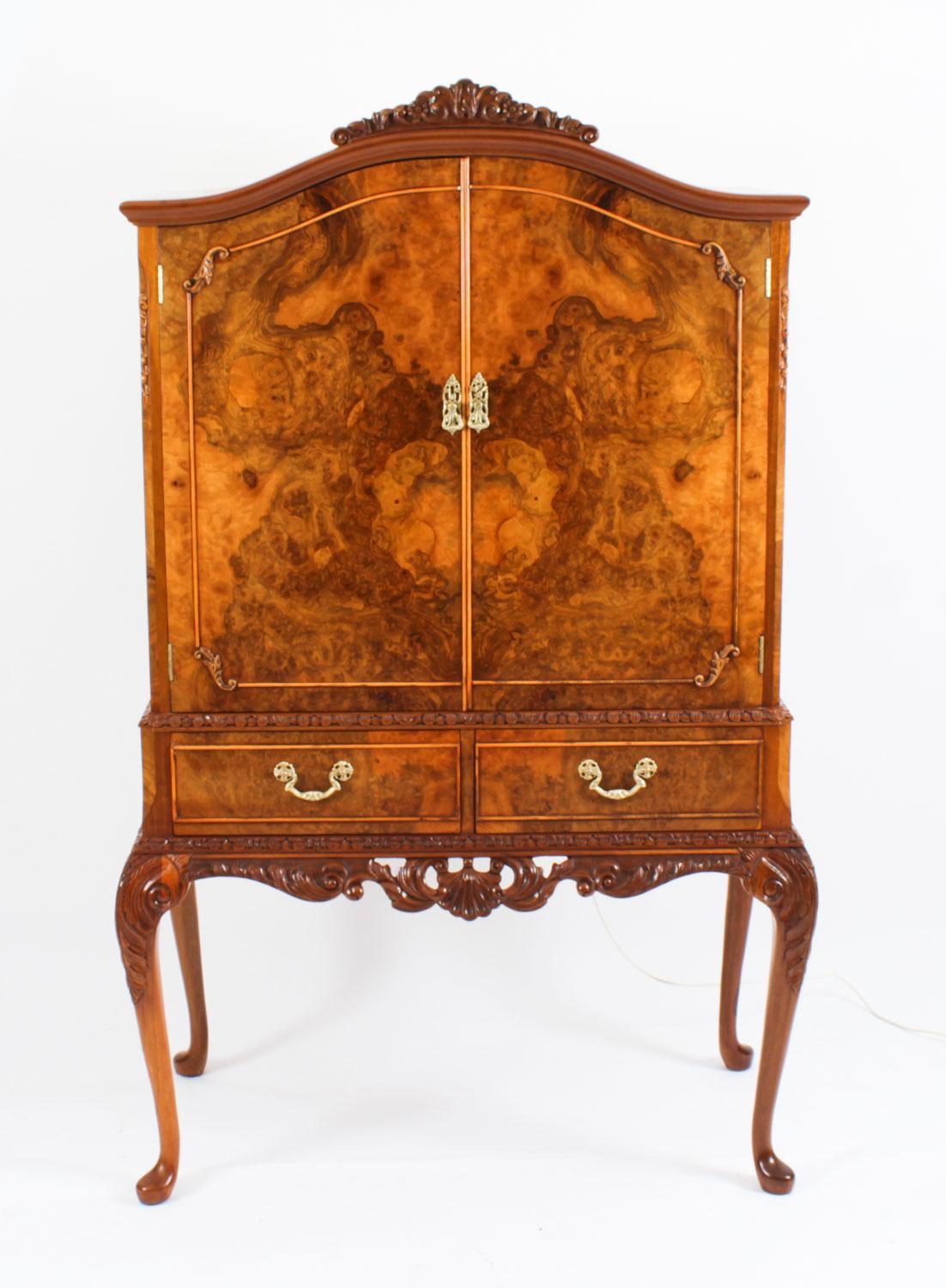 Il s'agit d'un fantastique meuble à cocktail en ronce de noyer de style Queen Anne Revival, avec une magnifique décoration sculptée à la main, datant des années 1930.
 
Les portes s'ouvrent pour révéler un superbe intérieur en miroir avec une