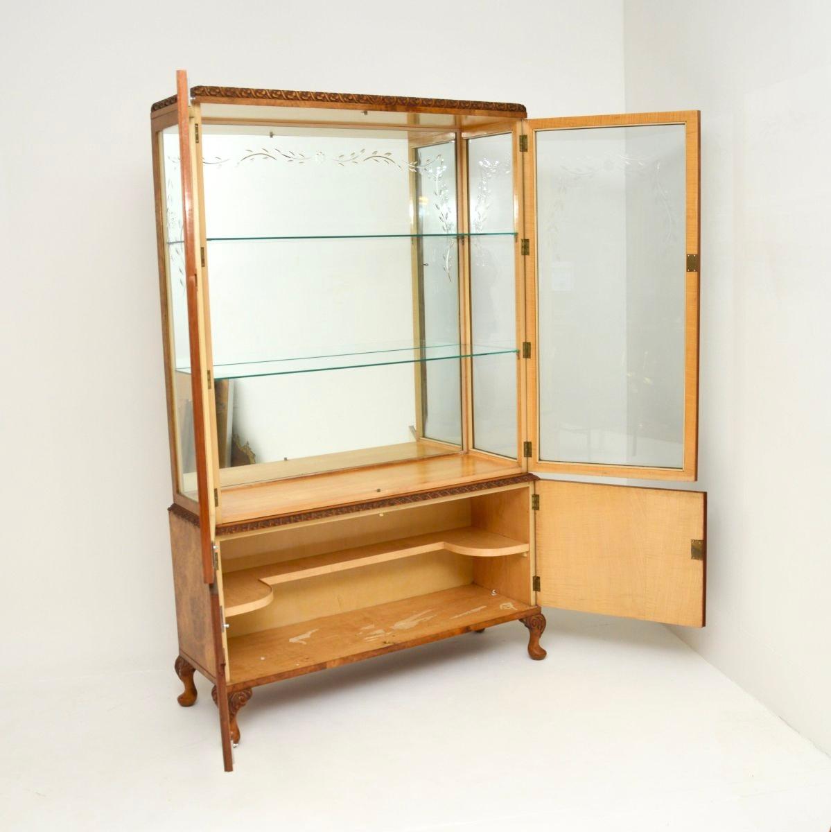 Magnífica vitrina antigua de nogal de estilo Queen Anne. Fabricado en Inglaterra, data aproximadamente de la década de 1930.

La calidad es excelente, tiene un bello e intrincado tallado alrededor de los bordes inferior y superior, se alza sobre