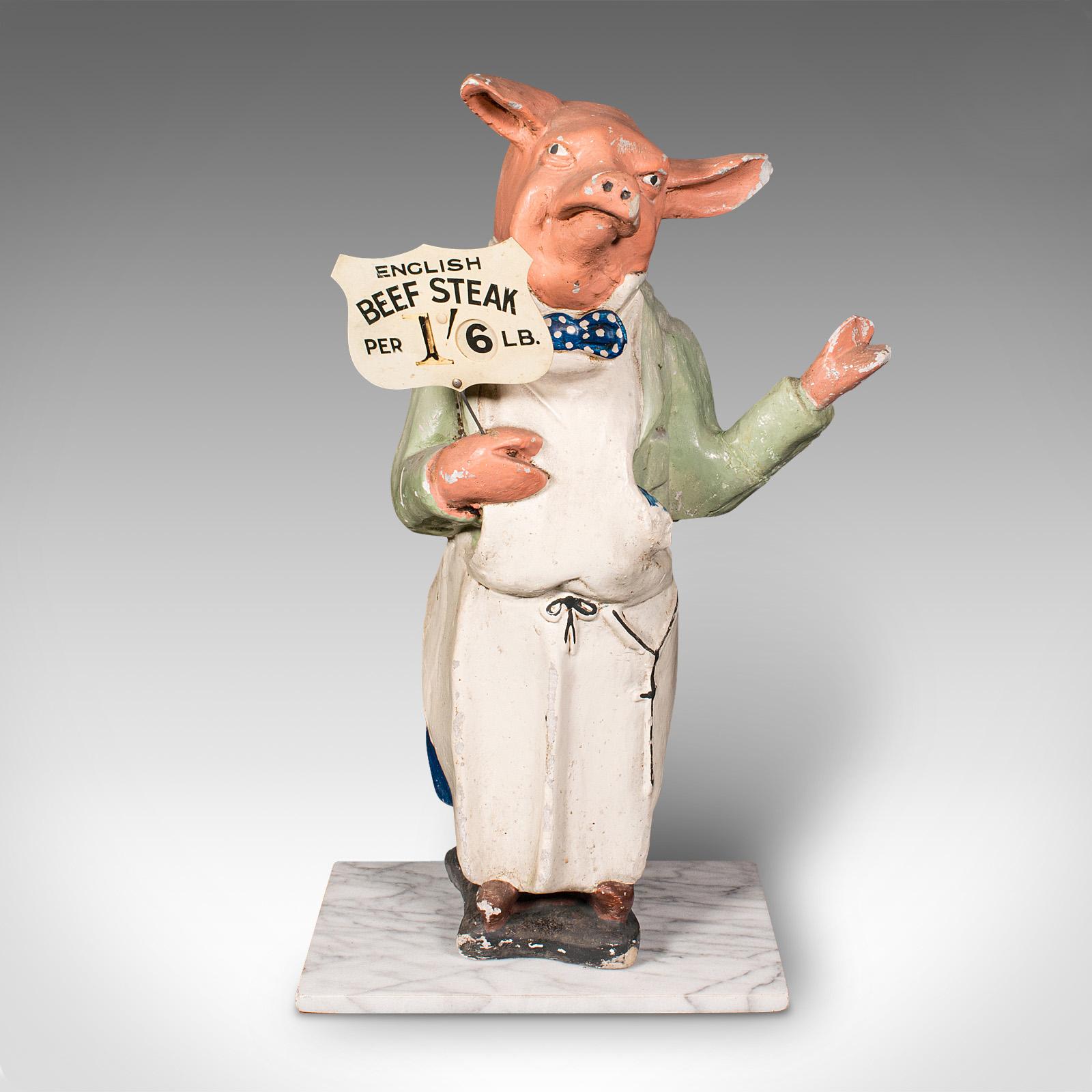 Se trata de una figura expositora de carnicería antigua. Cerdo publicitario comercial inglés de escayola con uniforme sobre zócalo de mármol, de la época eduardiana y posterior, hacia 1910.

Maravillosa historia del comercio británico con esta