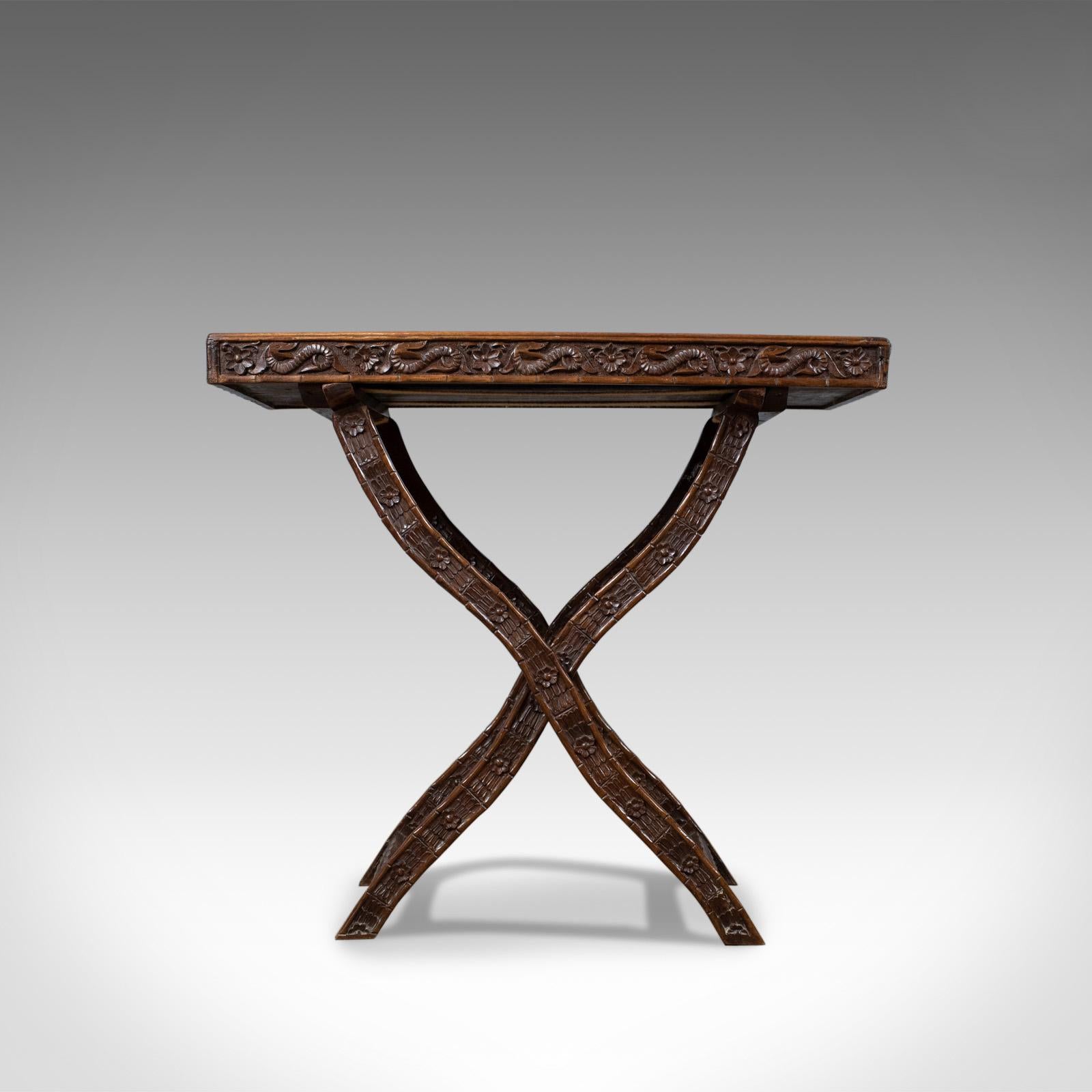 This is an antique butler's tray table, a carved oriental teak tray on folding stand dating to the early 20th century, circa 1900.

In fine order with delightful color and tone
Grain interest in the wax polished finish
Easily folds up for