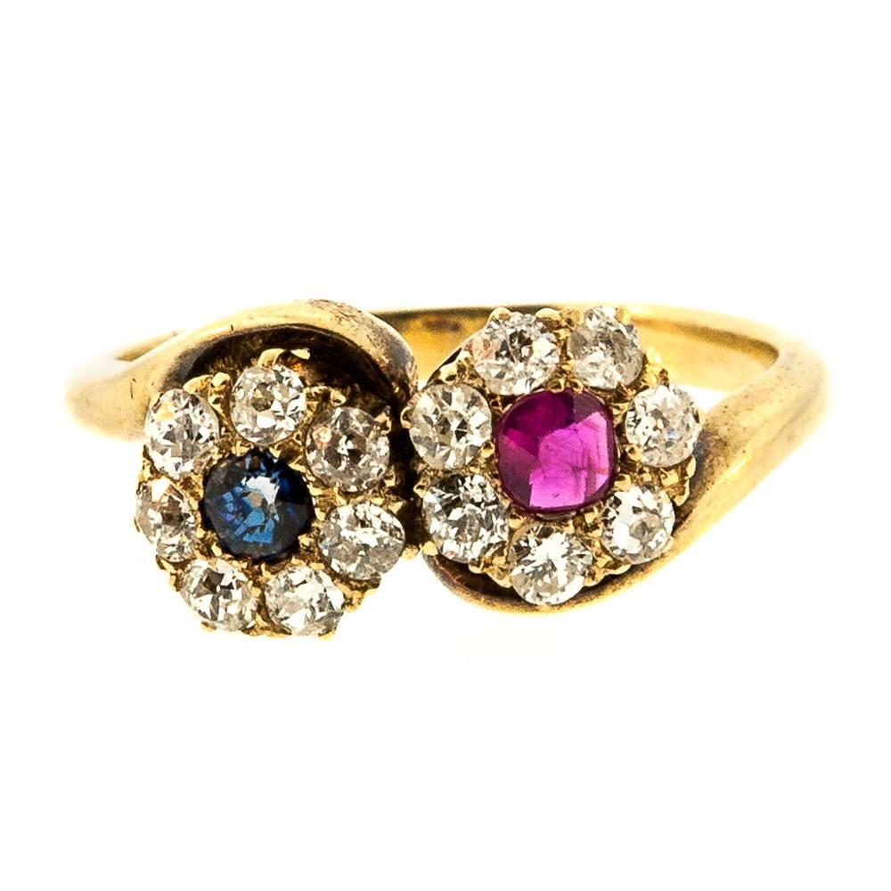 Romantically sweet this 1920s  14KT yellow gold bypass ring.  Designed with two clusters of Old Mine Cut Diamonds, one centers a 0.20 carat Star cut red Ruby,  and the other centers a 0.15 carat Star Cut blue Sapphire.   All diamonds are I/J color -