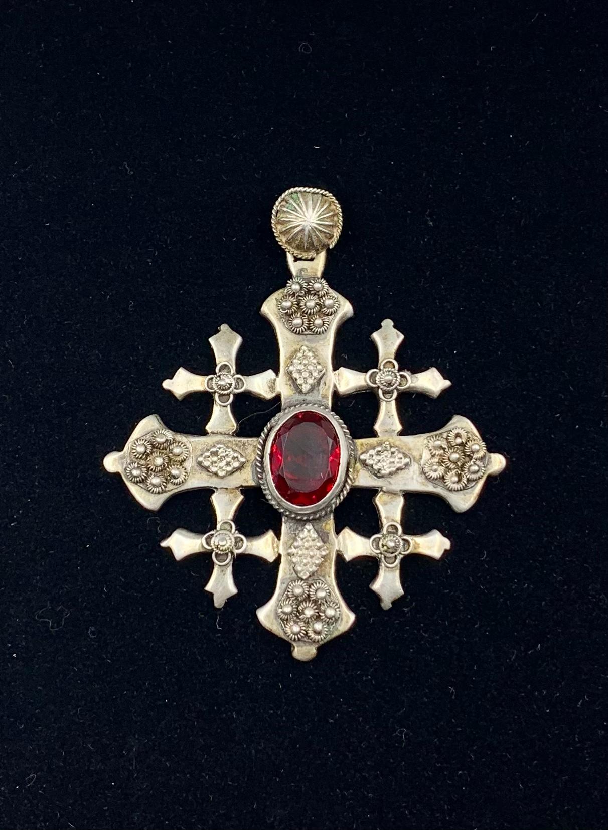 Beautiful Byzantine style large, substantial antique silver Five-Fold cross pendant with an oval faceted garnet glass center, granulation, silver wire decoration and a circular chased bale.
19th Century
The five-fold cross is symbolic of the five