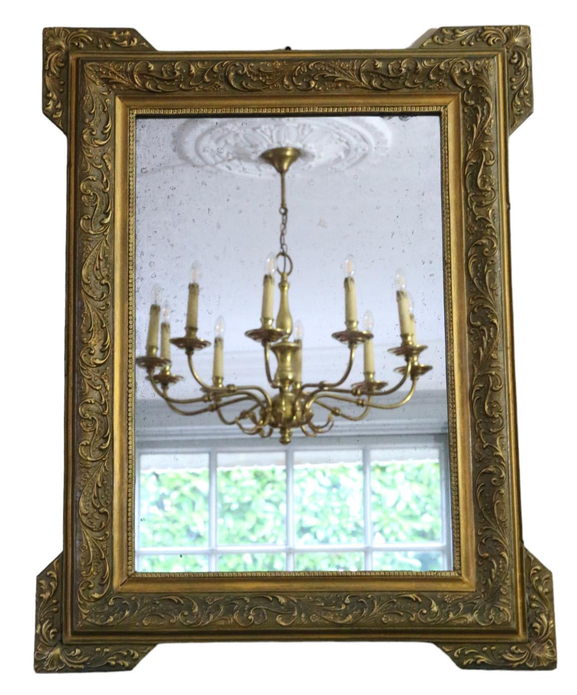 Antique C1900 large gilt overmantle wall mirror of fine quality, adorned with a decorative foliate design.

This mirror captivates with its simple yet striking design, lending character to any suitable space. The frame is free from loose