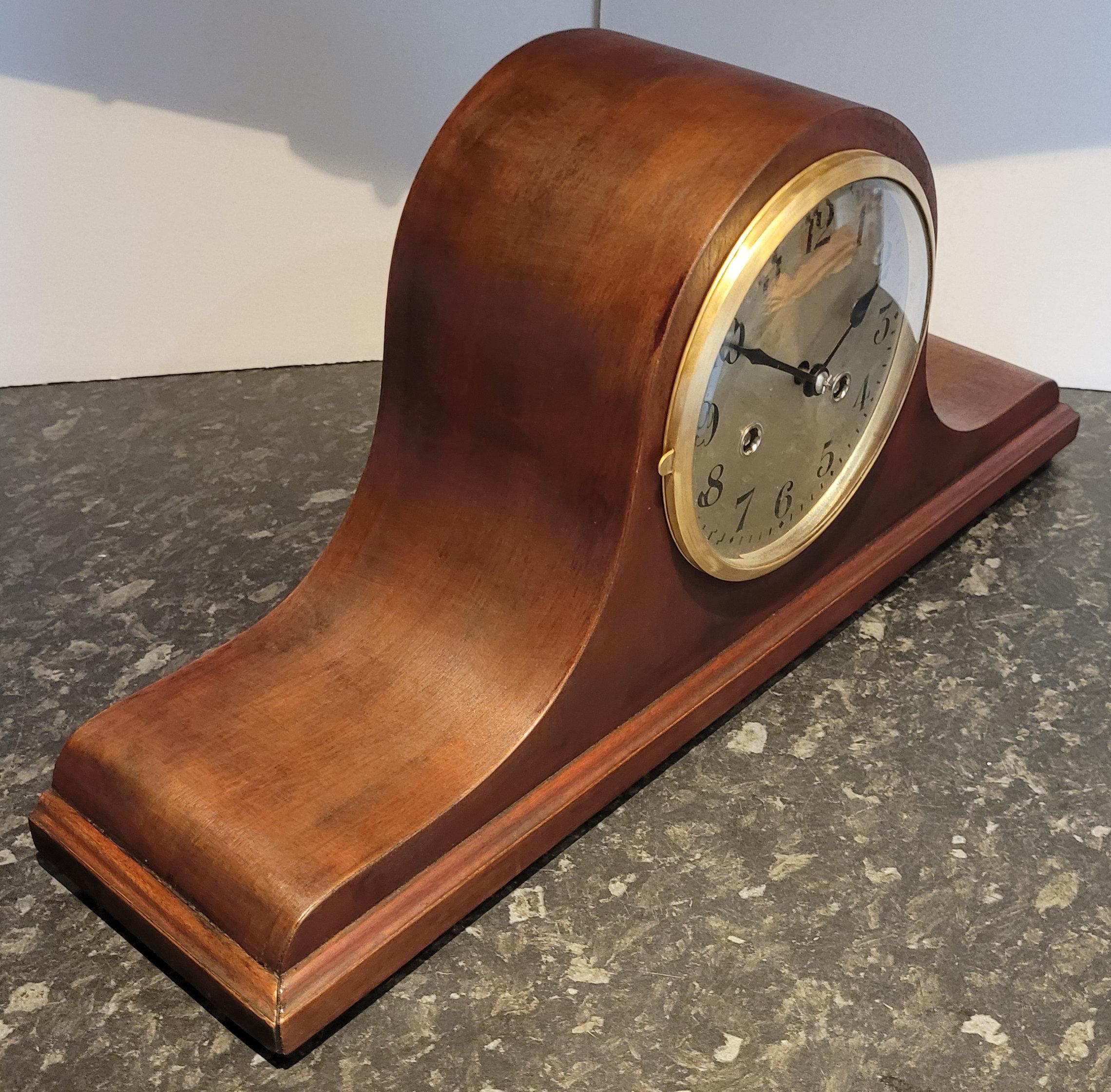 This is a antique early 20th century c1920's German chiming mantel clock. This is in excellent condition and is in full working order. It has a beautiful, long Napoleon hat shaped mahogany body raised on four bun feet. The mahogany has a rich cherry