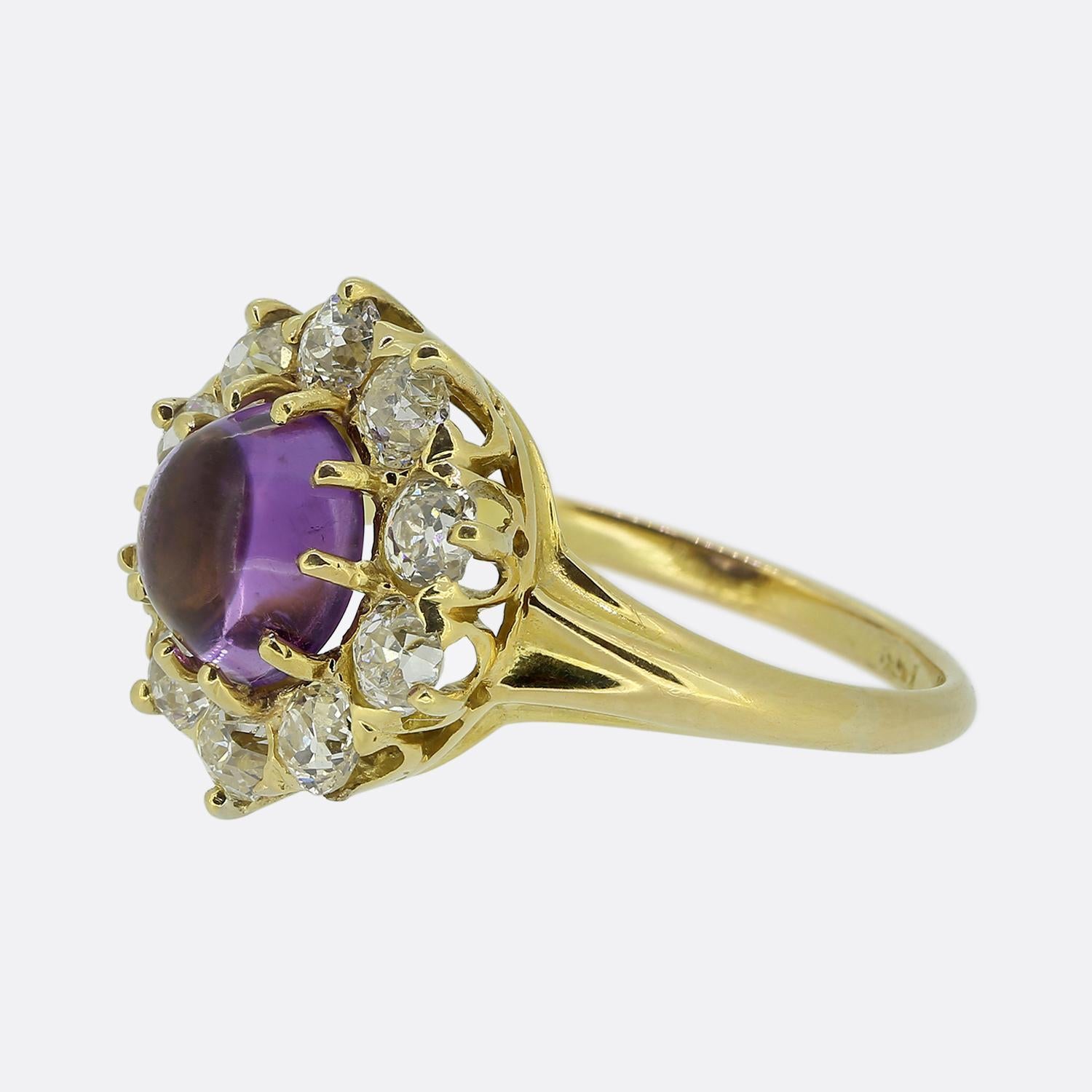 Here we have a charming cluster ring crafted from a rich 18ct yellow gold. At its heart lies a captivating purple cabochon-cut amethyst, radiating a soft, alluring glow. Surrounding this principal stone is a halo of round faceted old mine cut