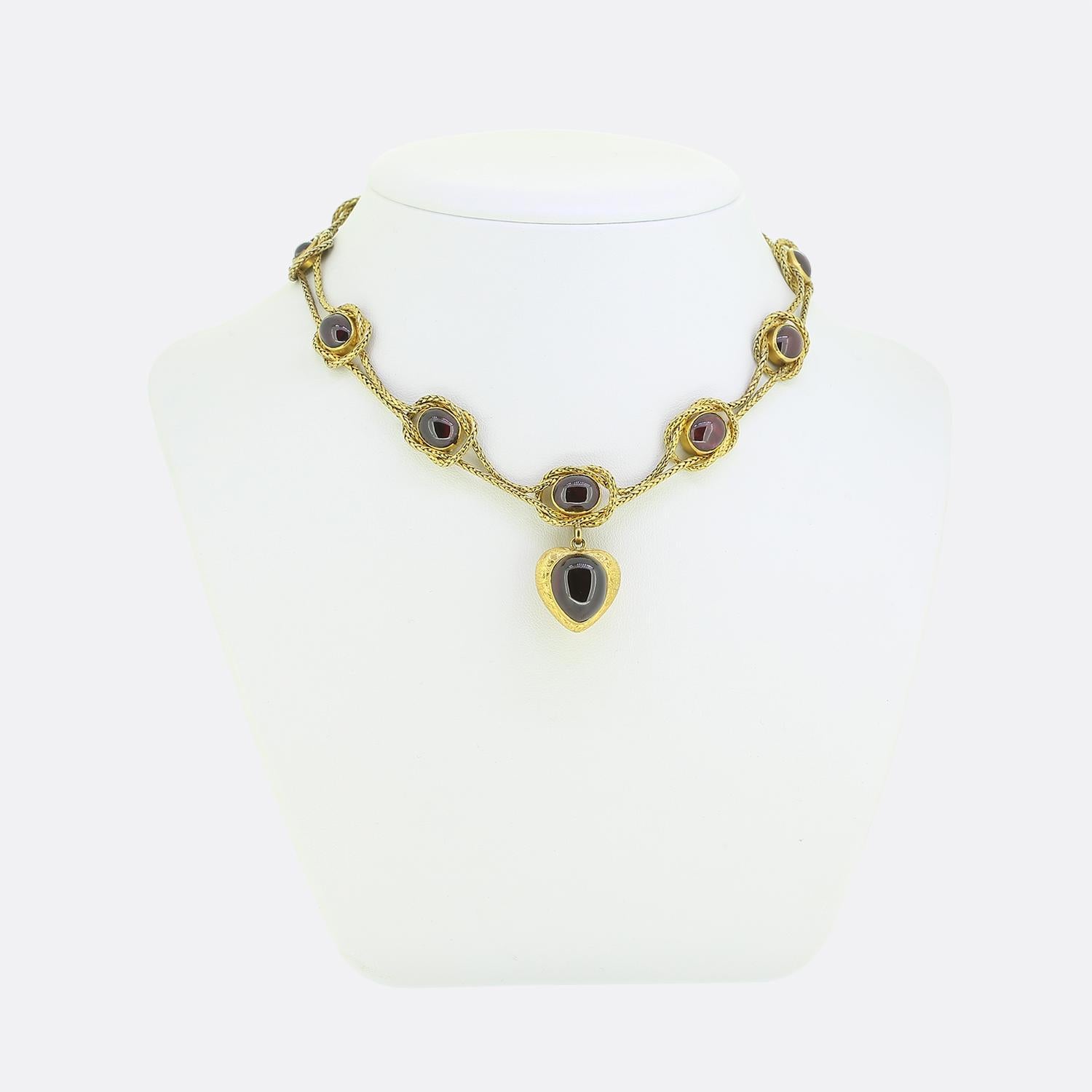 Ecco un'eccezionale collana risalente al periodo vittoriano. Questo pezzo d'antiquariato è stato realizzato a mano in oro giallo 18 carati con un paio di catene a serpente intrecciate che ospitano una serie di gemme cabochon di granato. Ogni granato