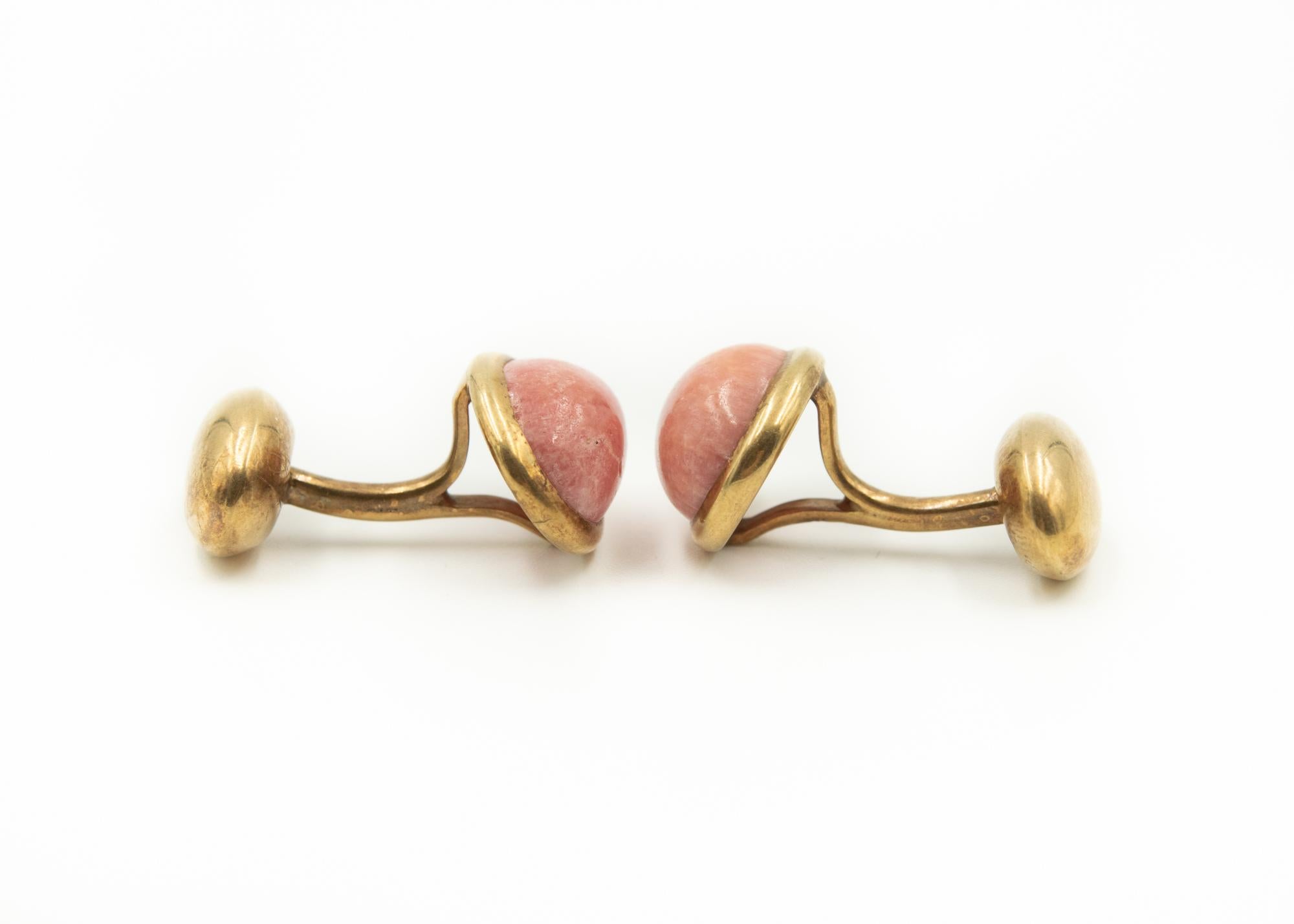 Antique cufflinks featuring oval pink rhodochrosite cabochons (measuring approximately 12mm x 8.5mm) set in an oval gold bezel.  On the other side is a smaller oval gold section.  The back is stationary and must be pushed through the slat in the