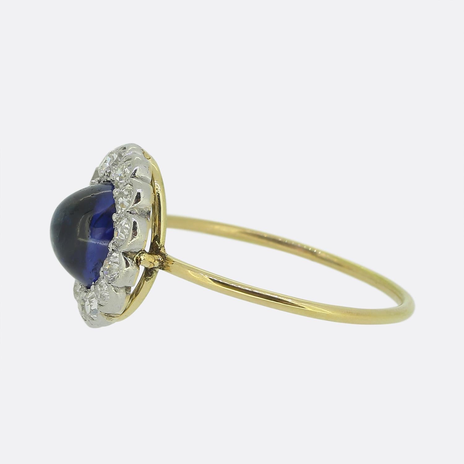 Nous avons ici une magnifique bague ancienne en saphir et diamant. Le saphir est taillé en cabochon d'un bleu intense et il est entouré d'une grappe de 15 diamants de taille ancienne. La bague est complétée par un anneau plus moderne en or jaune