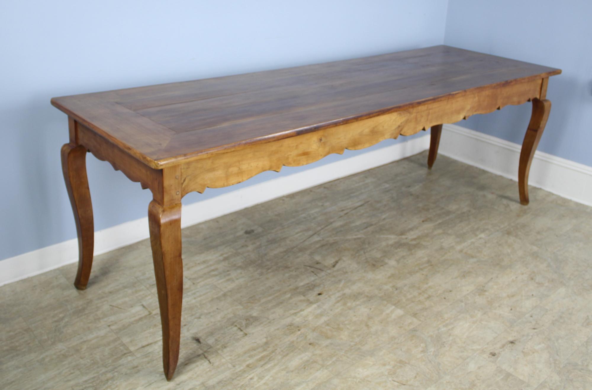 A long French dining or farm table with a whimsically carved apron in mellow glowing cherry. Though the dramatic curved cabriole legs are the star of the show. With 84.5 inches between the legs on the long side, this table could possibly seat 10.