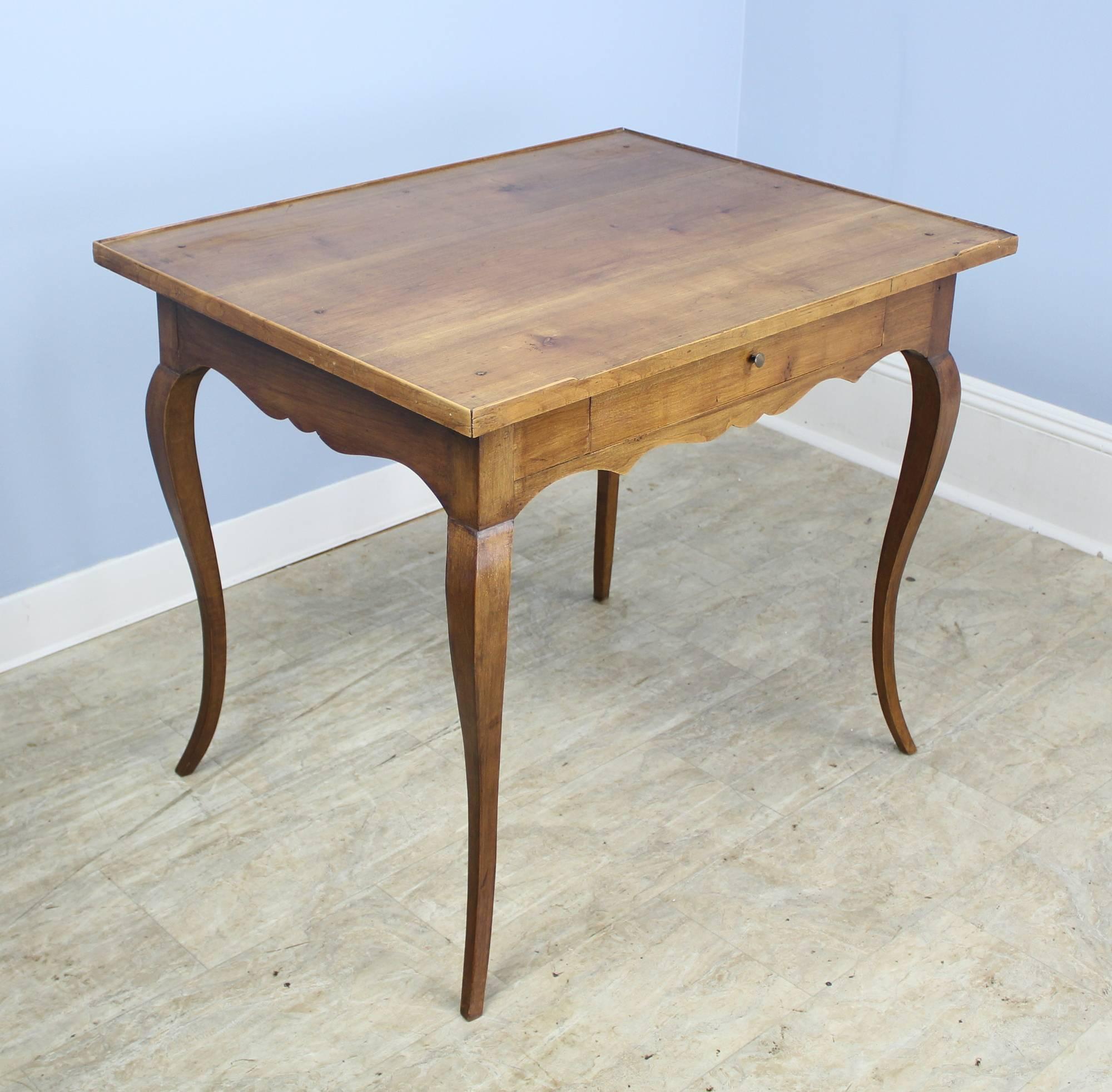 An elegant cabriole leg side, lamp, or occasional table in mellow walnut. The top has a slight galleried edge which adds a note of interest. The color and patina on this piece are very good. Single drawer slides easily.