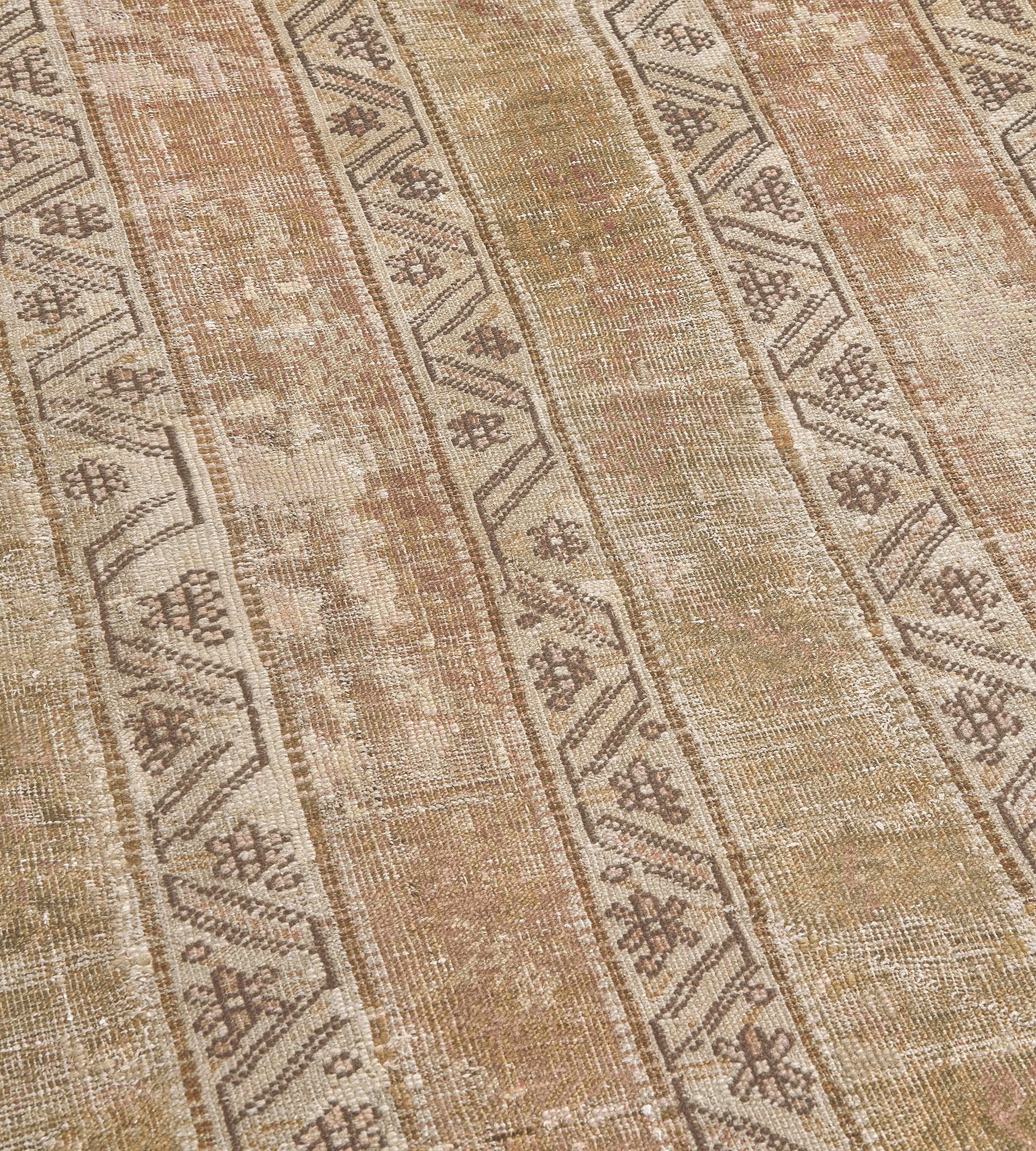 Ce chemin de table antique de Ghordes présente un champ central composé de quatre panneaux verticaux brun caramel flanqués de bandes étroites ivoire contenant un ruban de vigne brun taupe sinueux entourant des têtes de fleurs.

Les tapis anciens de