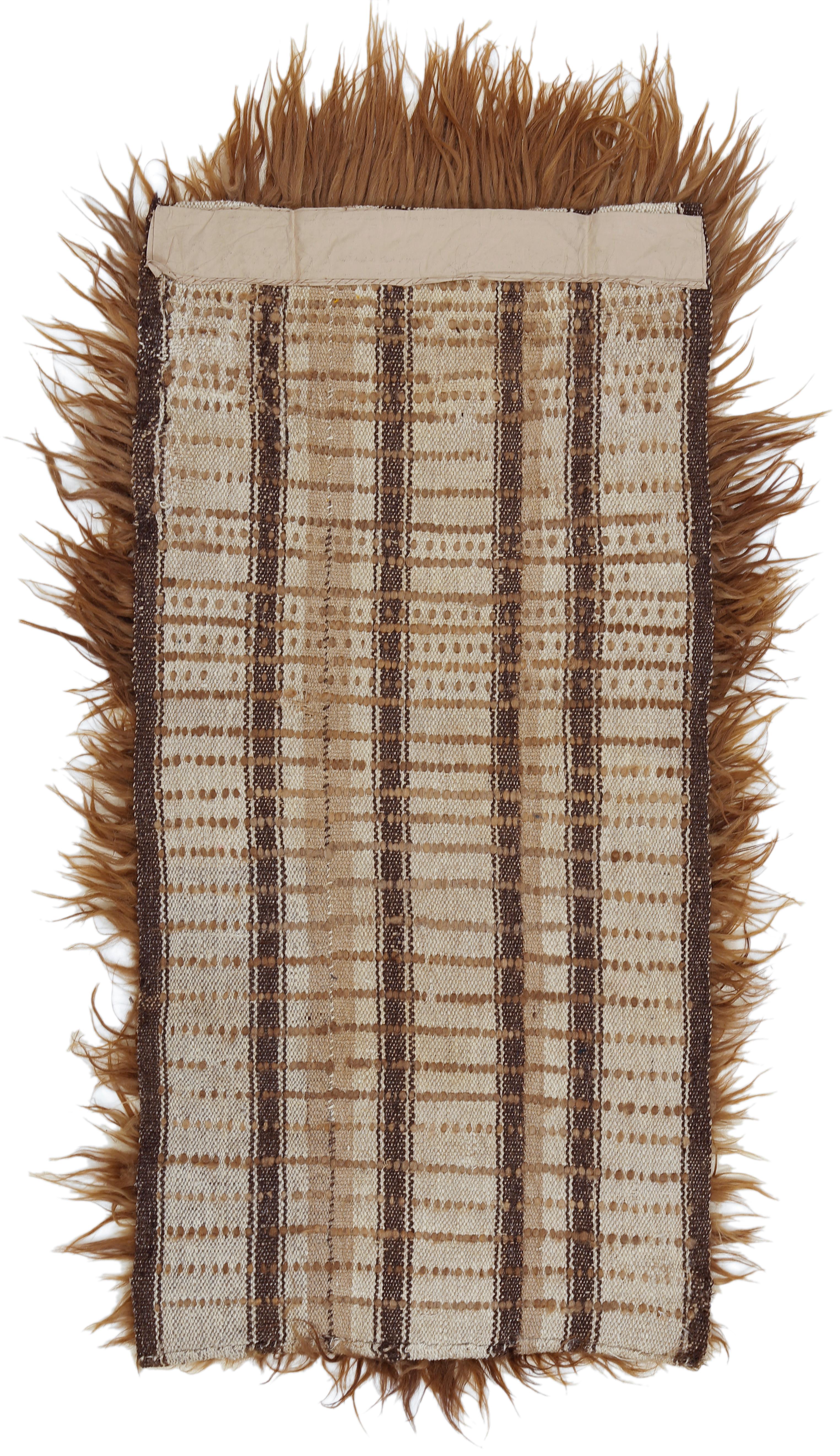 Ein sehr seltener Teppich aus der Taklamakan-Wüste im Nordwesten Chinas, der nur spärlich mit Strängen aus ungesponnenem Kamelhaar geknüpft ist. Jede Knotenreihe ist durch eine beträchtliche Anzahl von Wollschüssen getrennt, was zu einem Grundgewebe